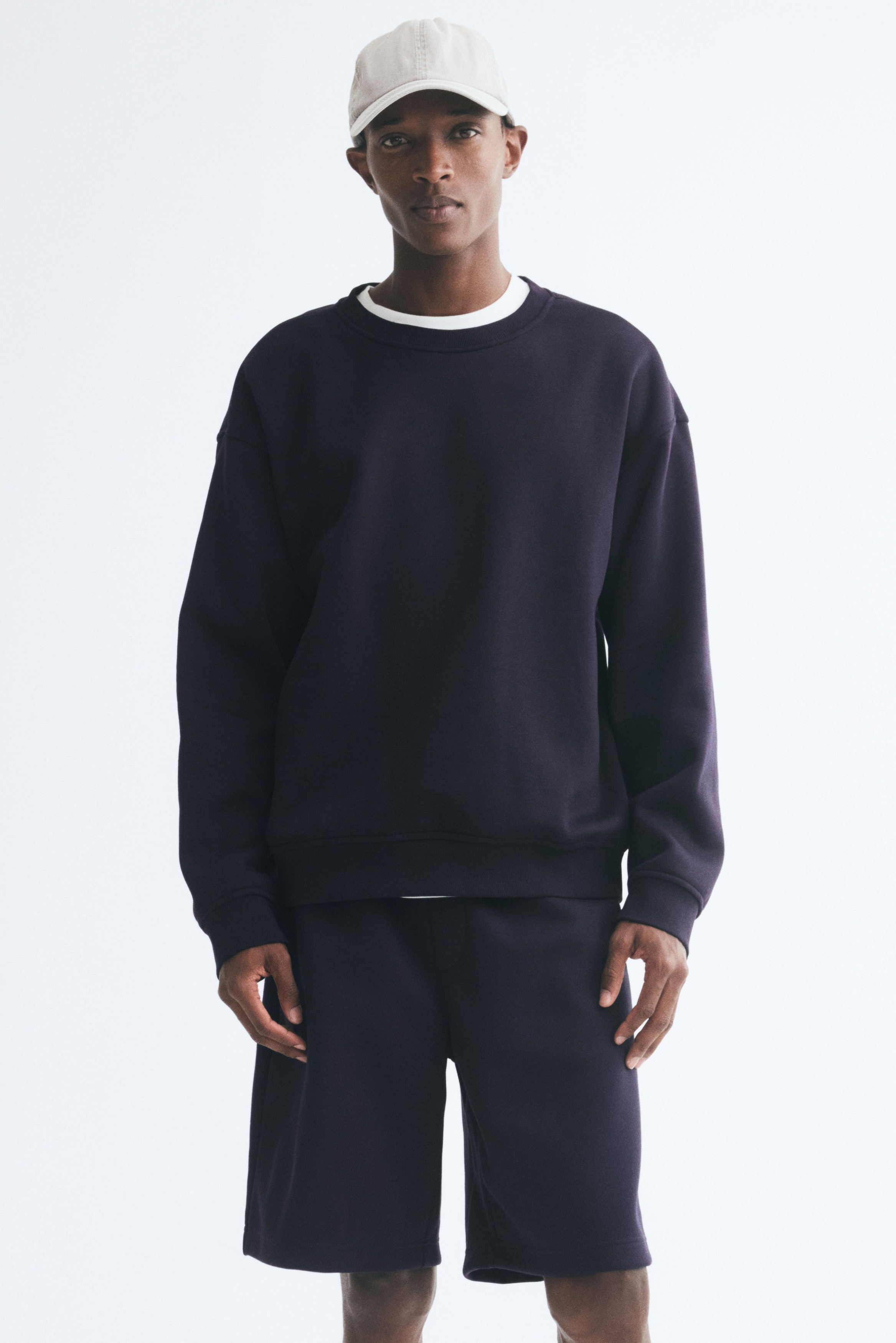 Navy shorts are shown front-facing, featuring an elasticated waistband, side-seam pockets, and a stitched faux fly detail.