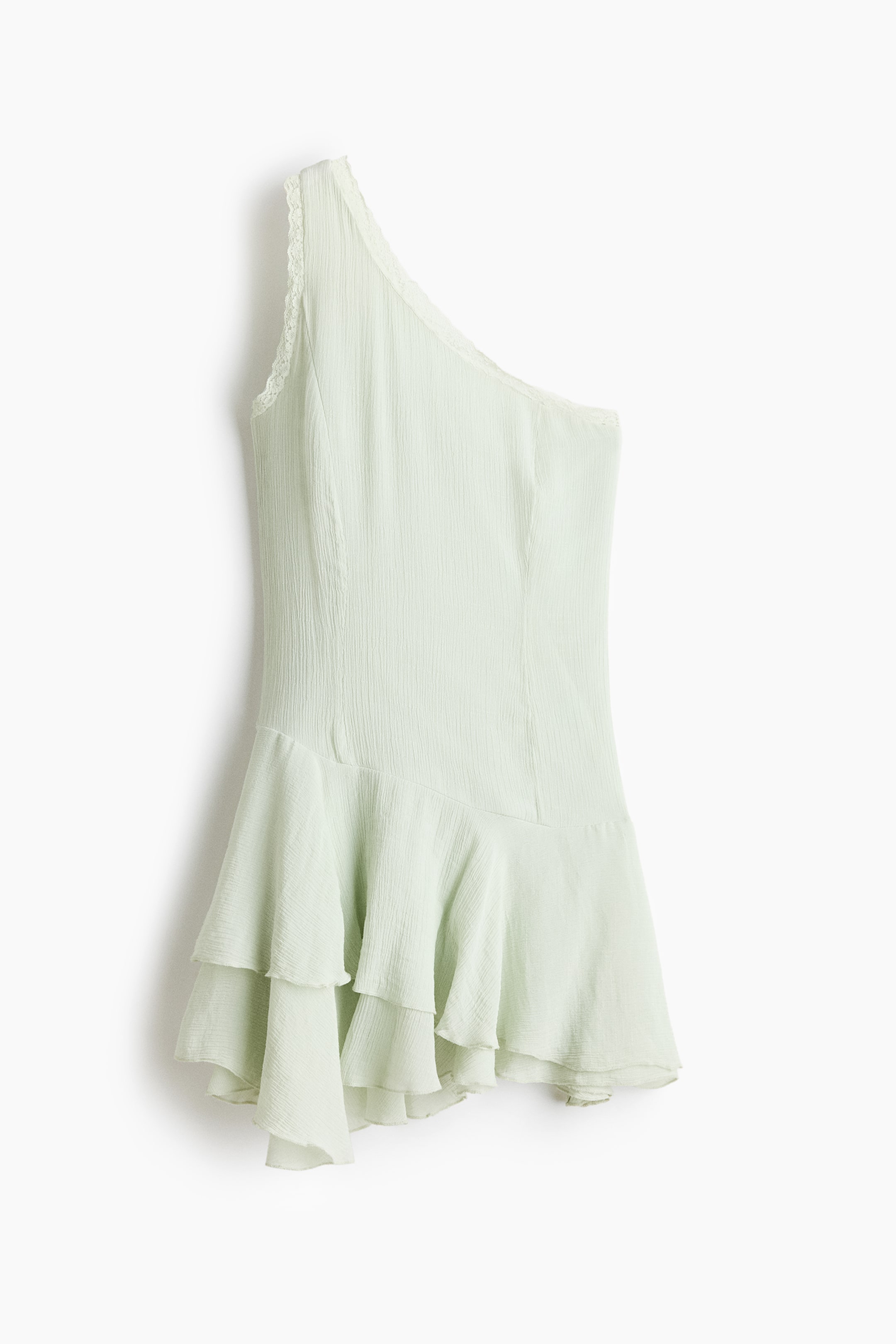 View larger image: A pale green one-shoulder dress is featuring a delicate lace trim along its single strap. The dress is presenting a crinkled texture and multiple ruffled tiers forming the skirt.