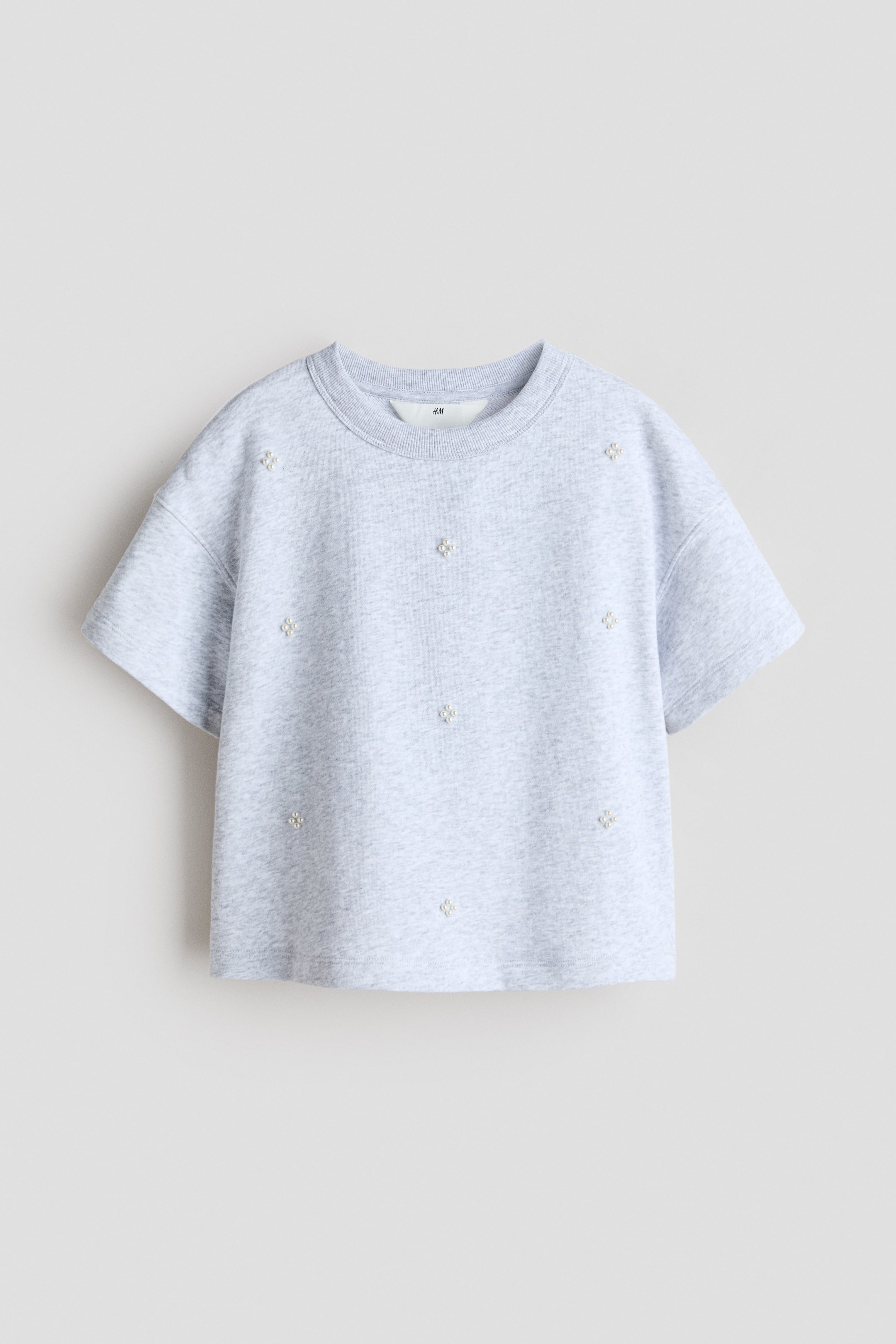 View larger image: A motif-detail jersey T-shirt, FRONT, is presented in a light grey marl colour with a loose fit, a round, rib-trimmed neckline, gently dropped shoulders, and small pearl-like motifs scattered across its front surface.