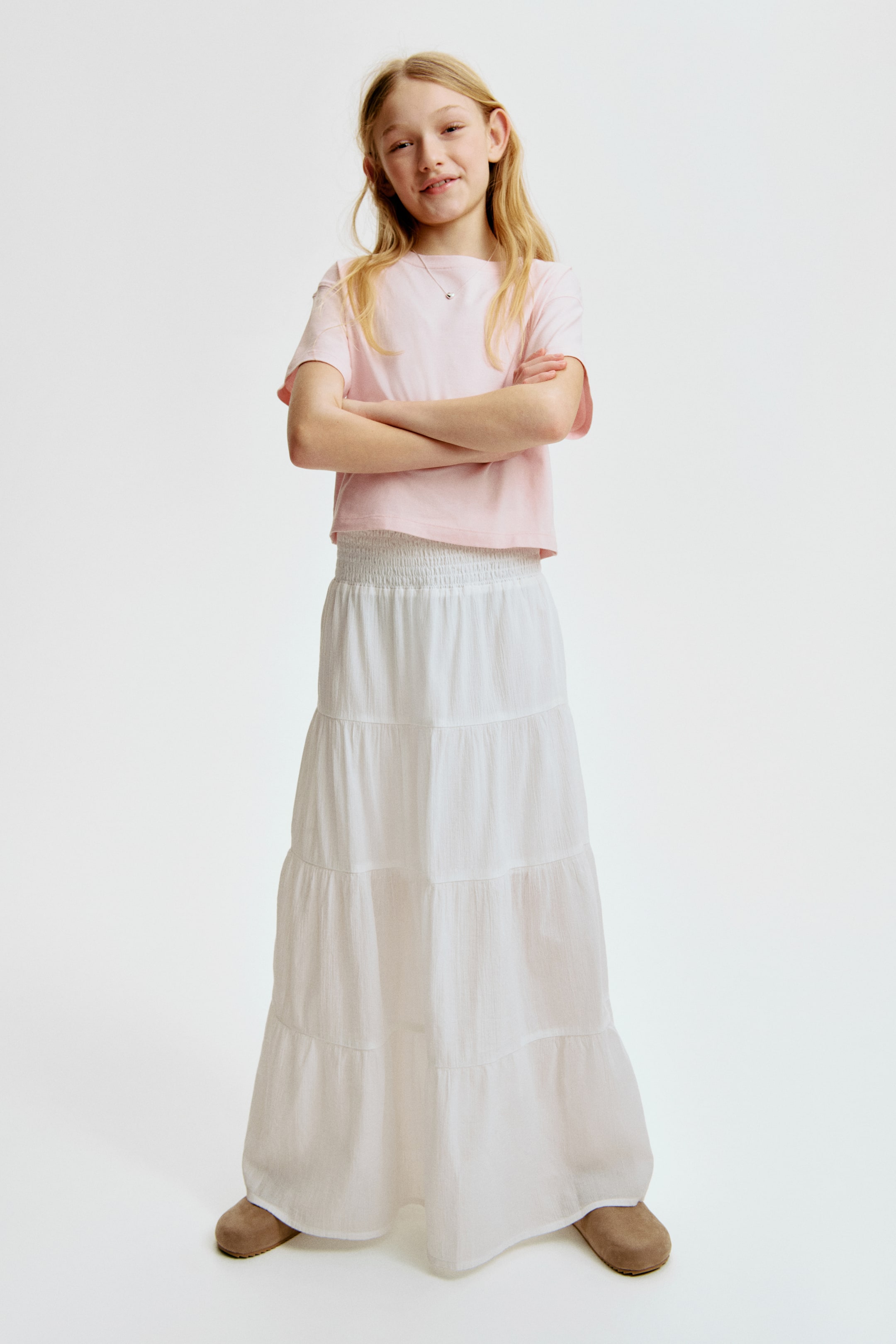 Ampliar la imagen: Una falda blanca, ligeramente en línea A, con capas, se presenta desde el frente, con un tejido aireado y una pretina fruncida.