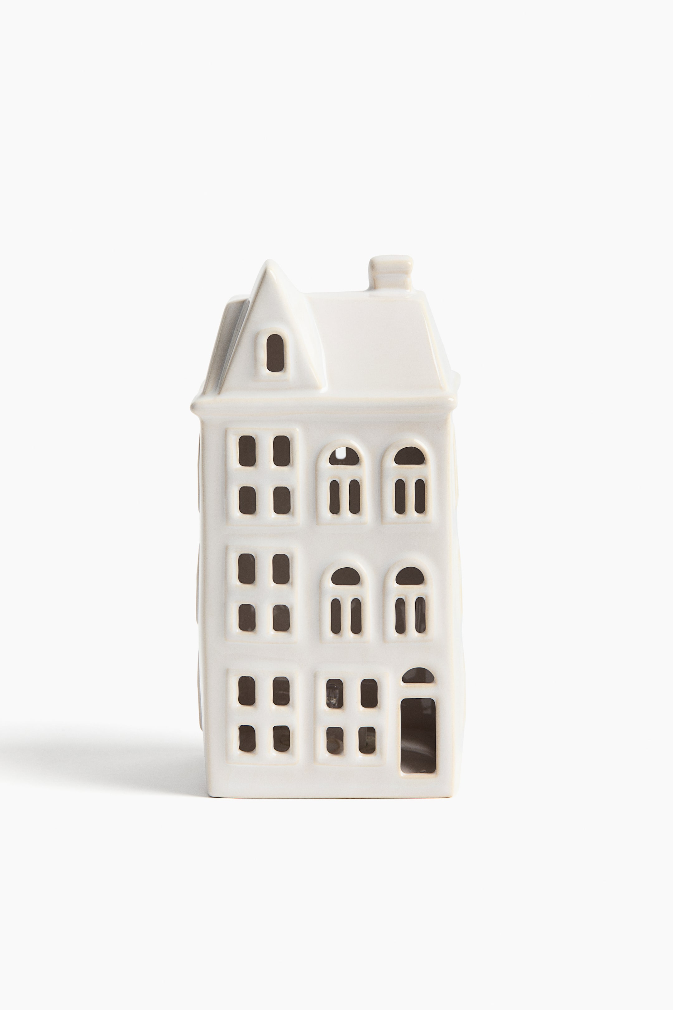 View larger image: A white ceramic house features a pointed roof with a chimney. Its front facade displays multiple cut-out windows, including square, arched, and dormer shapes, along with an open doorway.