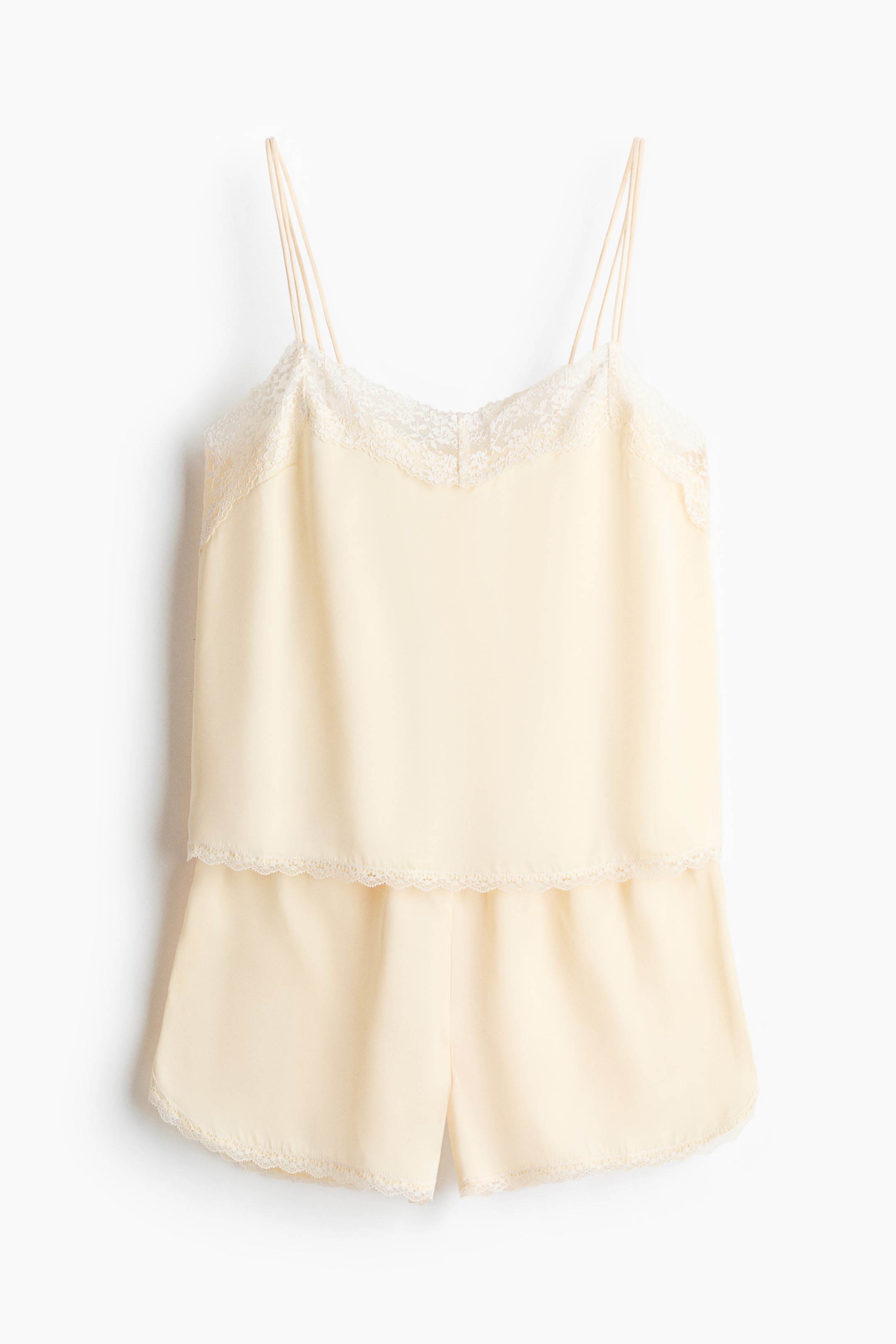 View larger image: A pyjama set features a top and shorts, both crafted in softly draping, light yellow satin. The top showcases a gently V-shaped neckline, double spaghetti shoulder straps, and lace trims along its neckline and lower edge. The shorts are designed with covered elastication at the waist and matching lace trims along the leg openings.