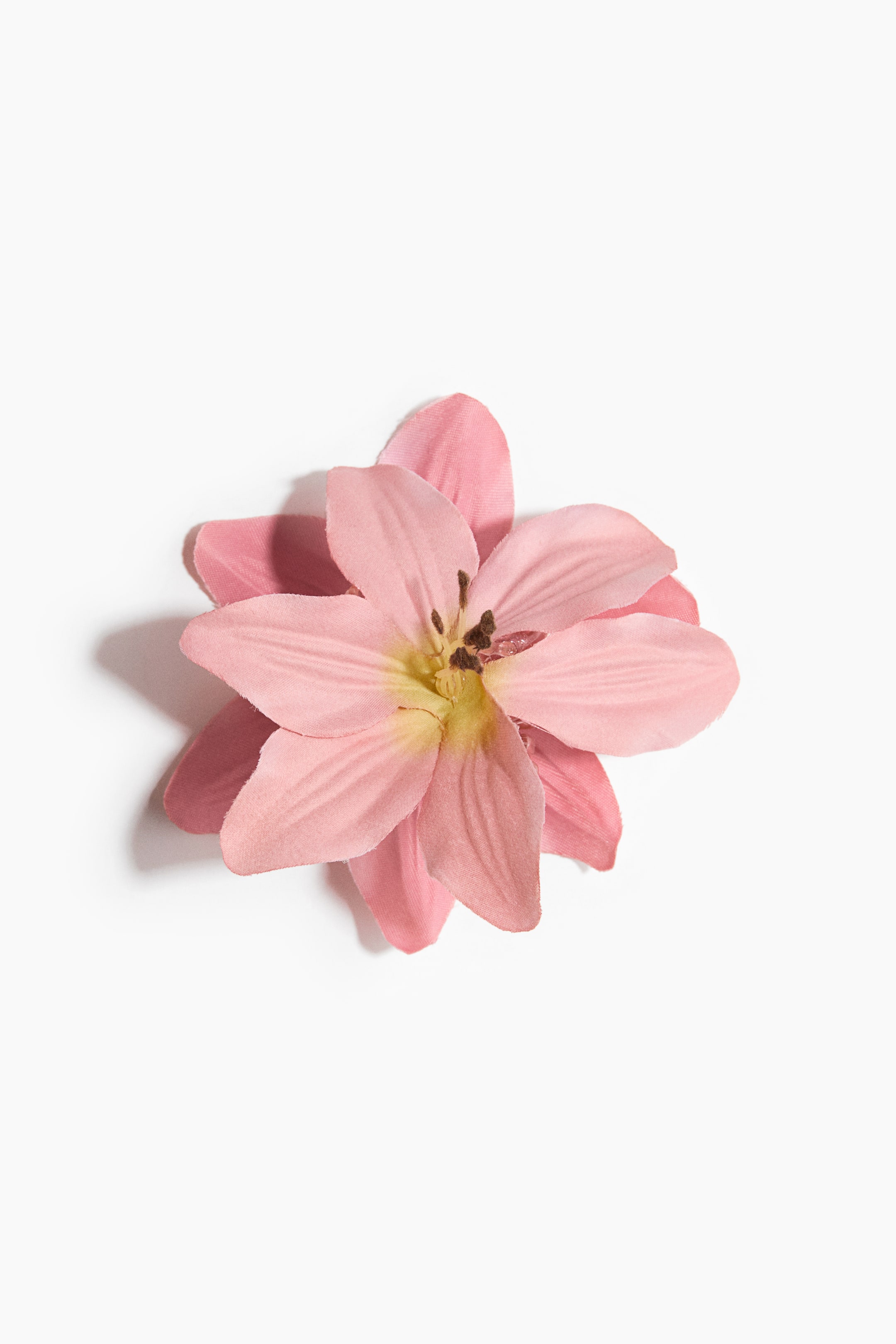 Visa större bild: En framåtvänd konstgjord blomma med flera lager av rosa kronblad, som visar ett gulgrönt centrum med mörkbruna ståndarliknande strukturer.