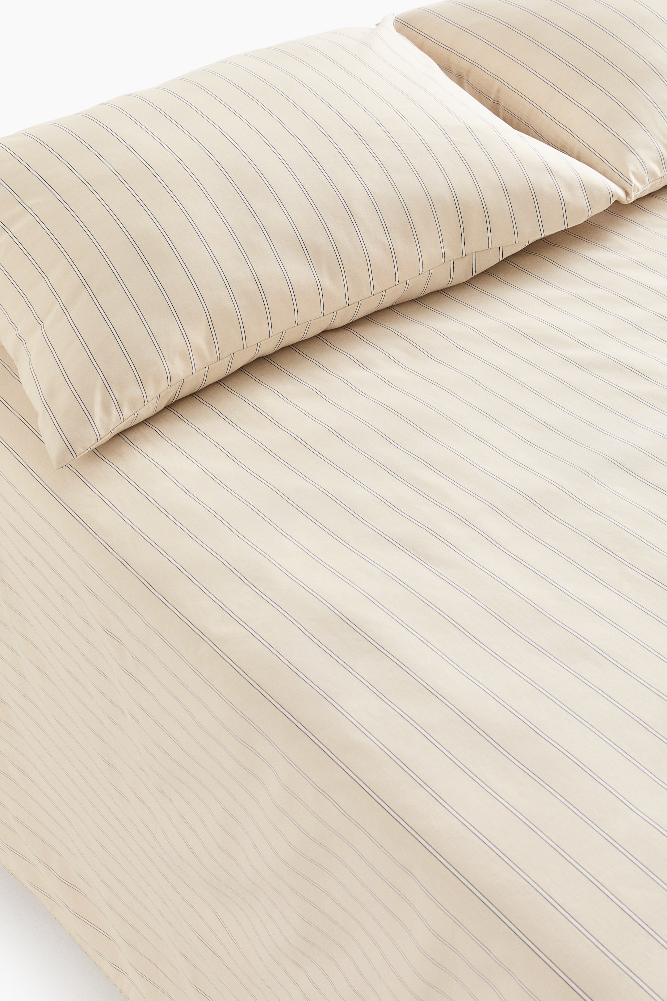 View larger image: A double/king bed sheet set is showing one flat sheet and two matching pillowcases, viewed from an overhead, slightly angled perspective. The light cream-coloured fabric features thin, dark, parallel stripes running consistently across all pieces.