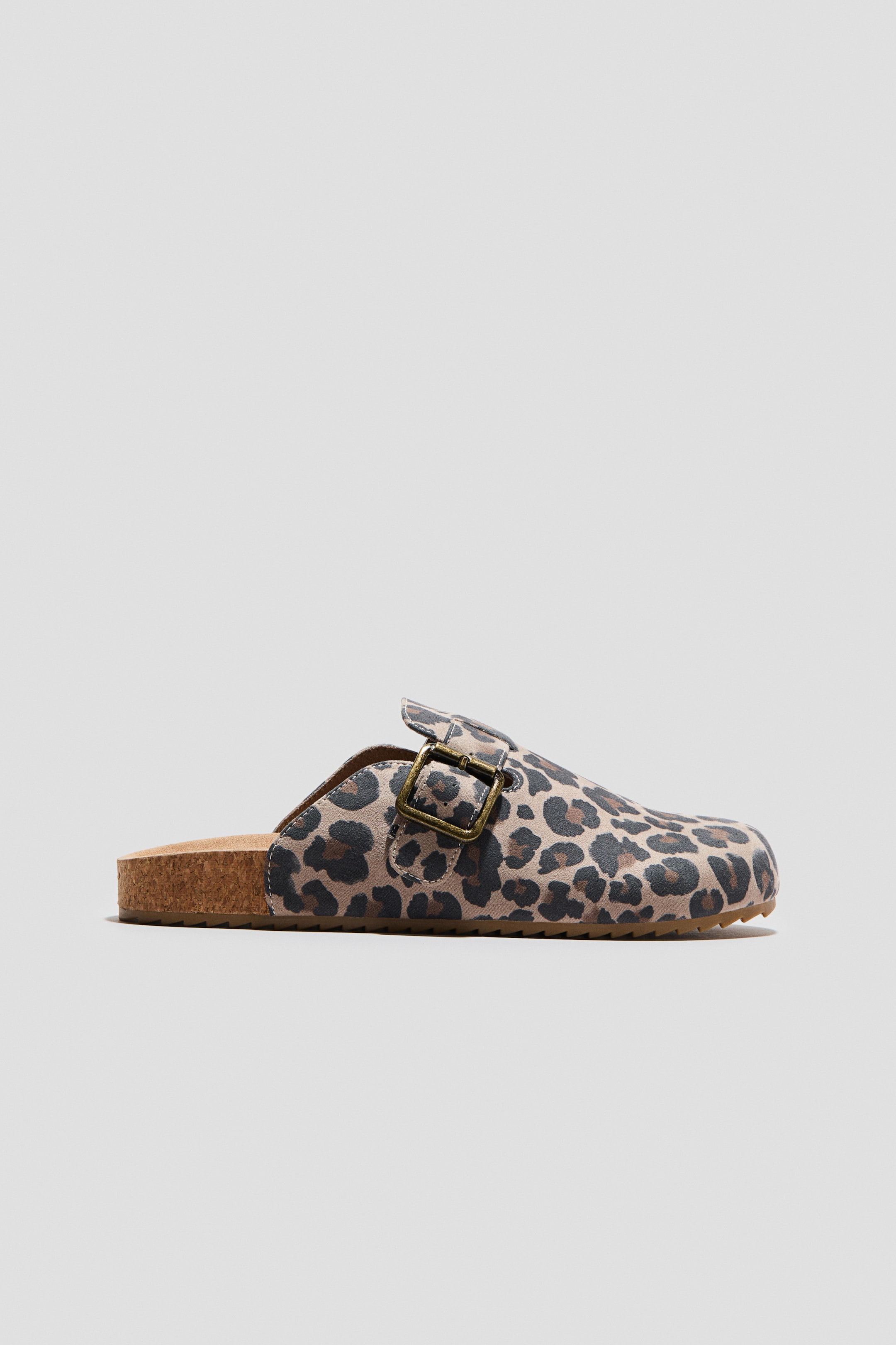 Ver imagen más grande: Un zueco con estampado de leopardo se presenta en vista lateral, con una parte superior en estampado de leopardo en beige, marrón y negro, acompañado de una hebilla de latón antiguo. Muestra una entresuela de corcho visible y una suela exterior de goma marrón.