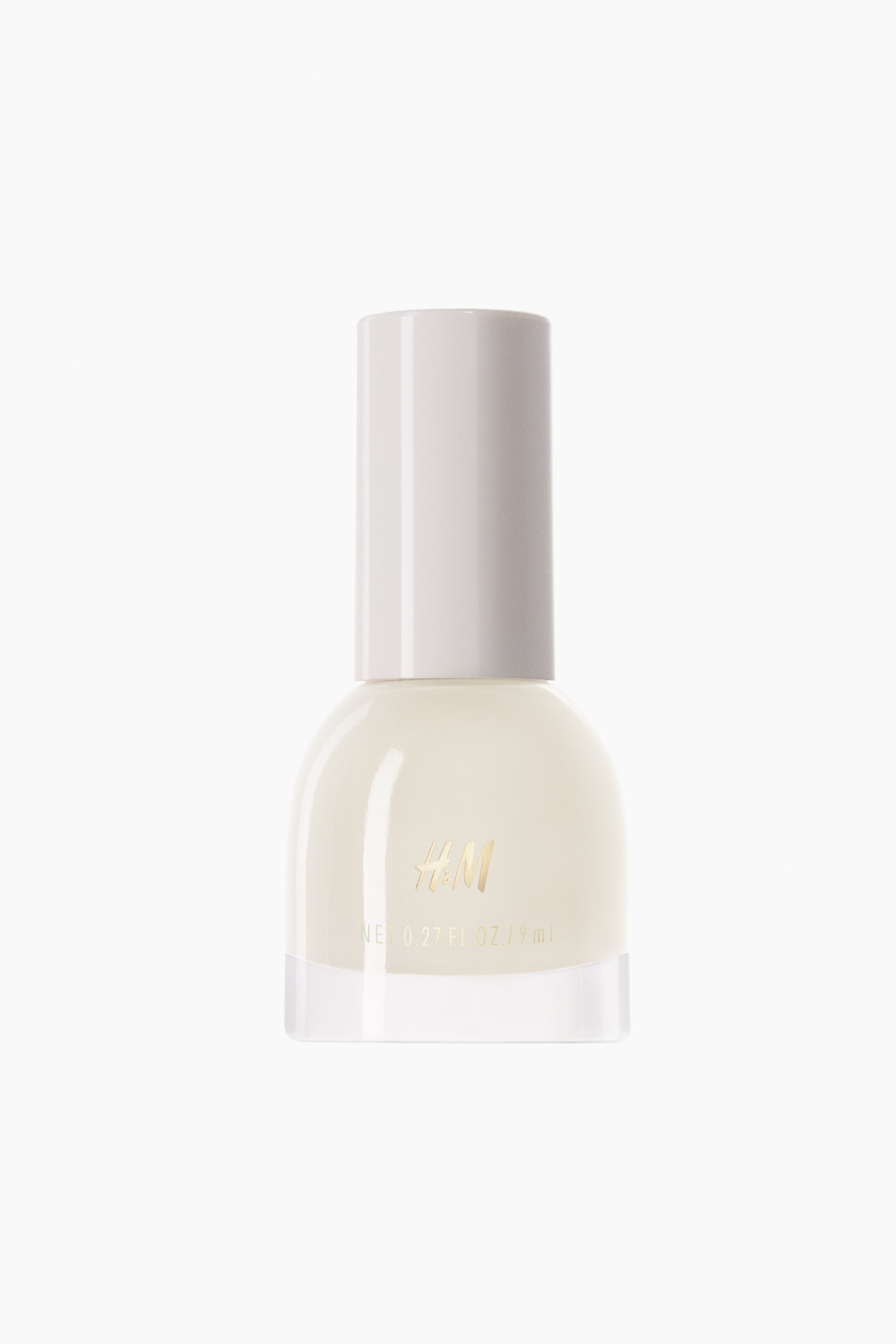 View larger image: The nail polish bottle is oriented forward, showcasing a transparent glass base filled with a creamy, off-white polish, and crowned with a matching off-white cylindrical cap. The front of the bottle prominently displays a gold "H&M" logo alongside the text "NET 0.27 FL. OZ. / 9 ml."