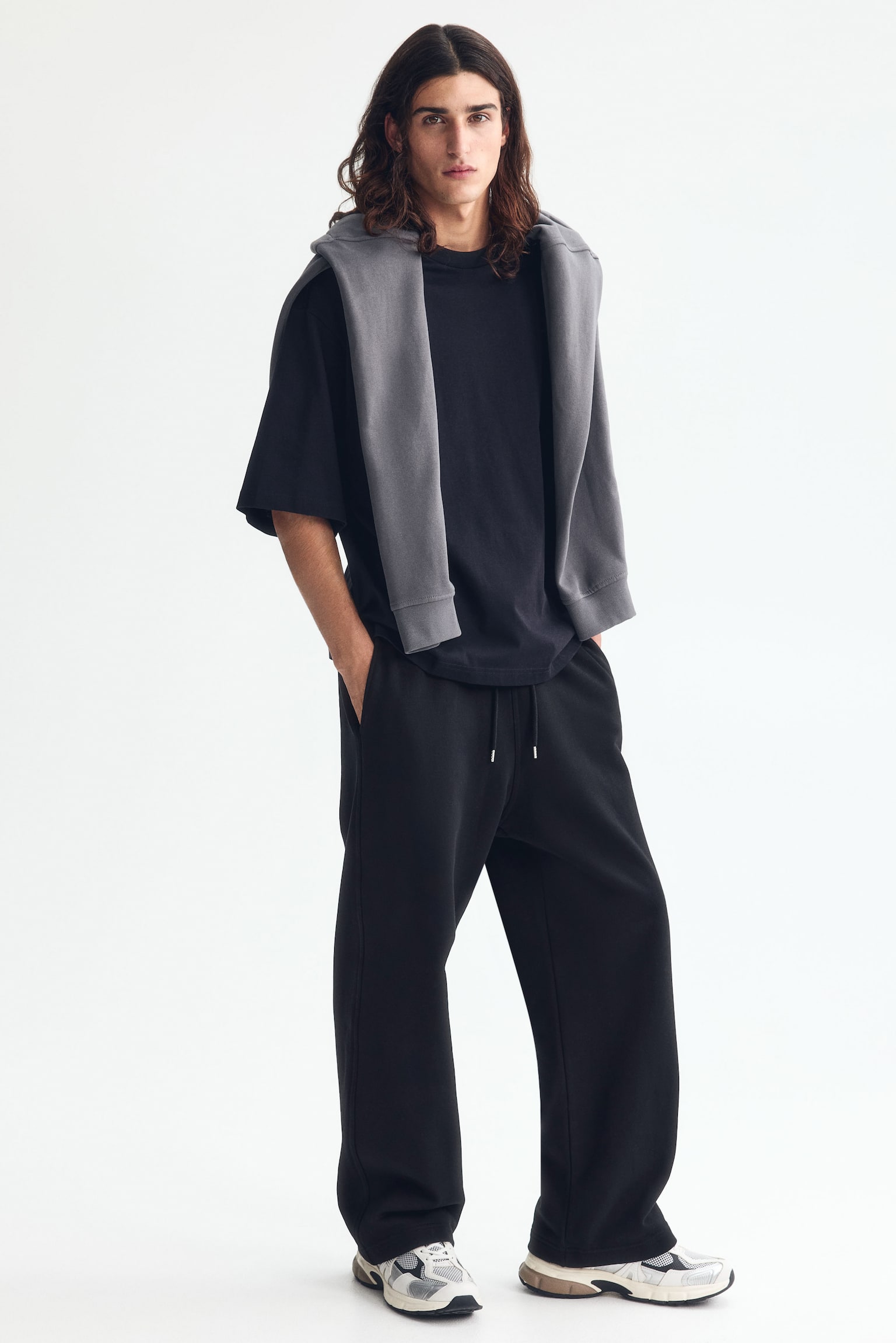 Black sweatpants crafted from cotton sweatshirt material showcase a front view, boasting a covered elasticated waistband with a drawstring that finishes in silver-toned metal tips. They also feature side pockets and offer a relaxed fit with straight legs. - 1