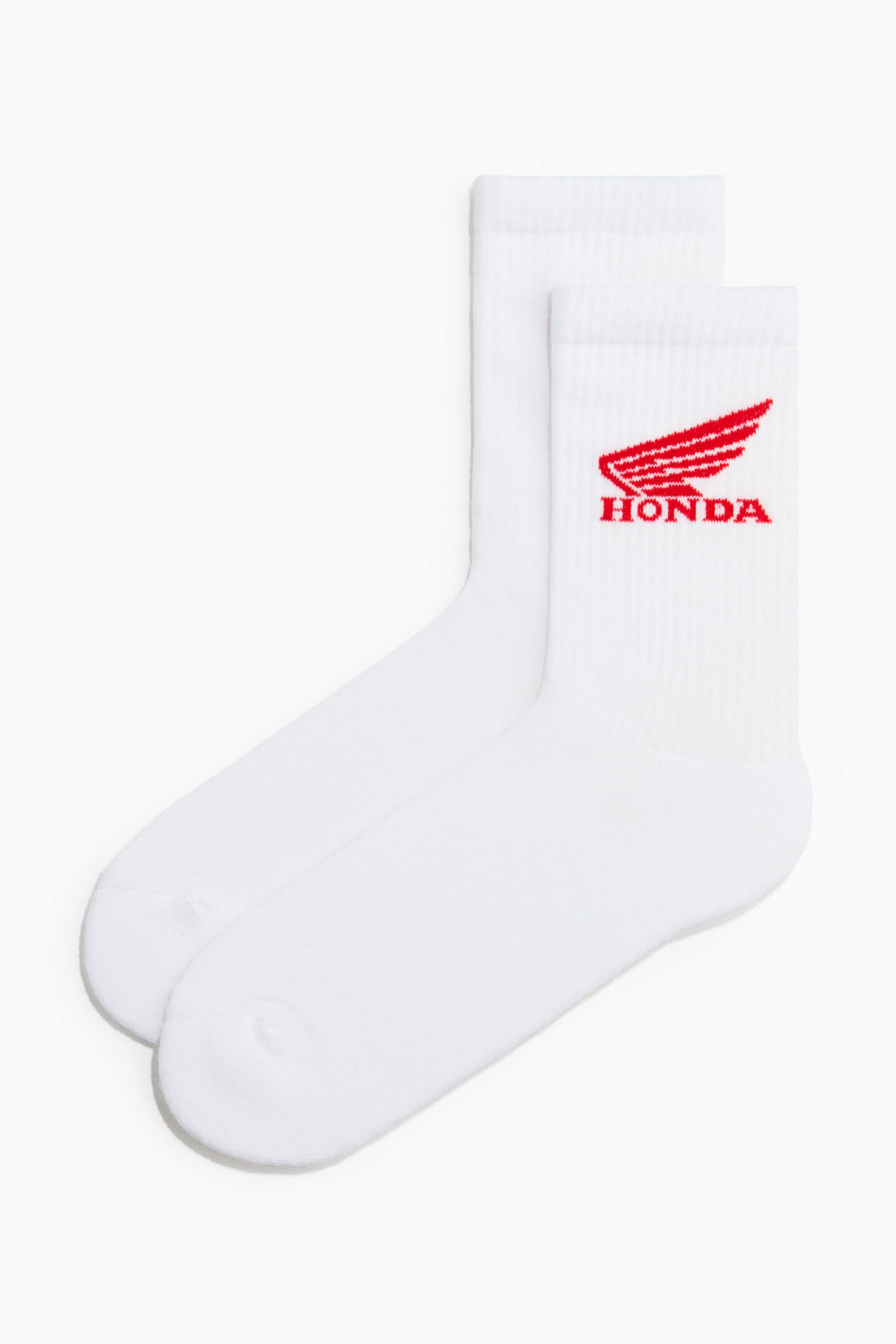 Xem ảnh lớn hơn: Một đôi tất trắng đang được trưng bày với cổ cao và có gân. Một chiếc tất có một biểu tượng có cánh màu đỏ và dòng chữ "HONDA" ở bên ngoài của nó.