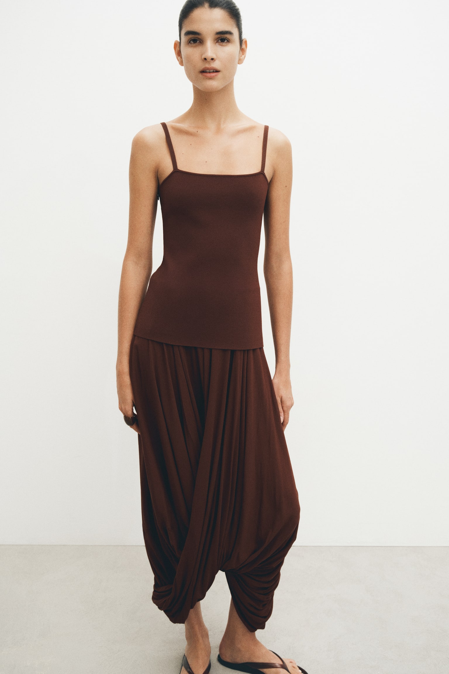 A dark brown camisole top with thin straps and a square neckline is being worn with matching dark brown draped trousers, which are gathering voluminously at the ankles. - 1
