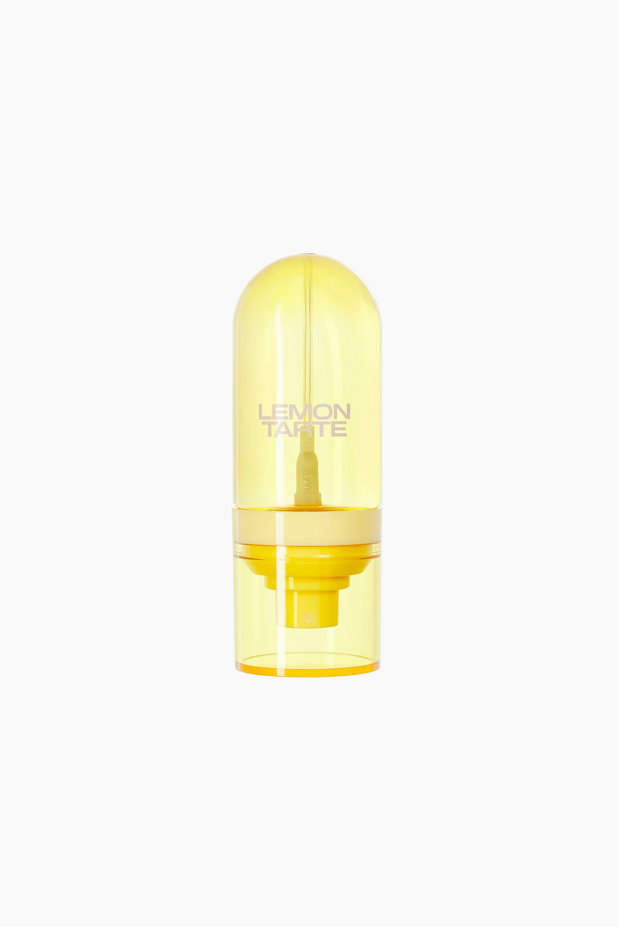 View larger image: A translucent yellow hair and body mist bottle stands upright. It features a rounded, capsule-shaped cap and a cylindrical base, with "LEMON TARTE" printed on its upper section.