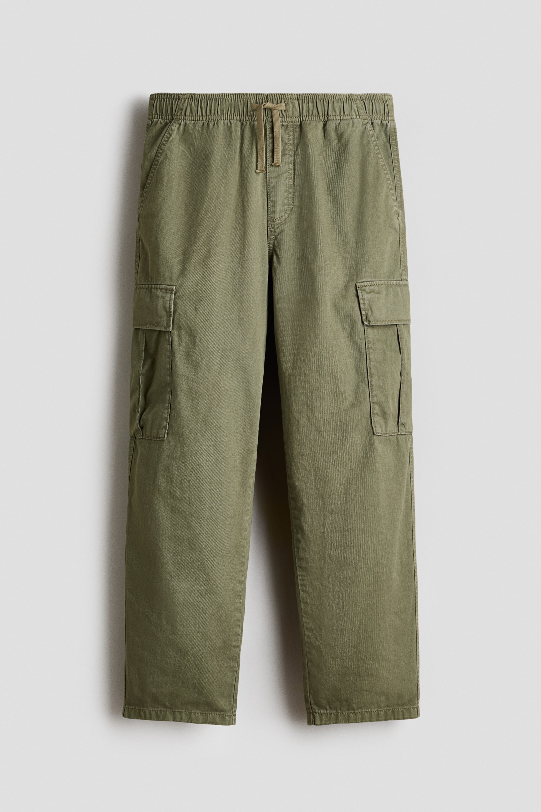 View larger image: Olive green cargo trousers are displayed facing front, featuring an elasticated waistband with a central drawstring, two slant pockets at the hips, and two flap cargo pockets on the outer thighs. The trousers are designed with a straight leg and a plain hem.