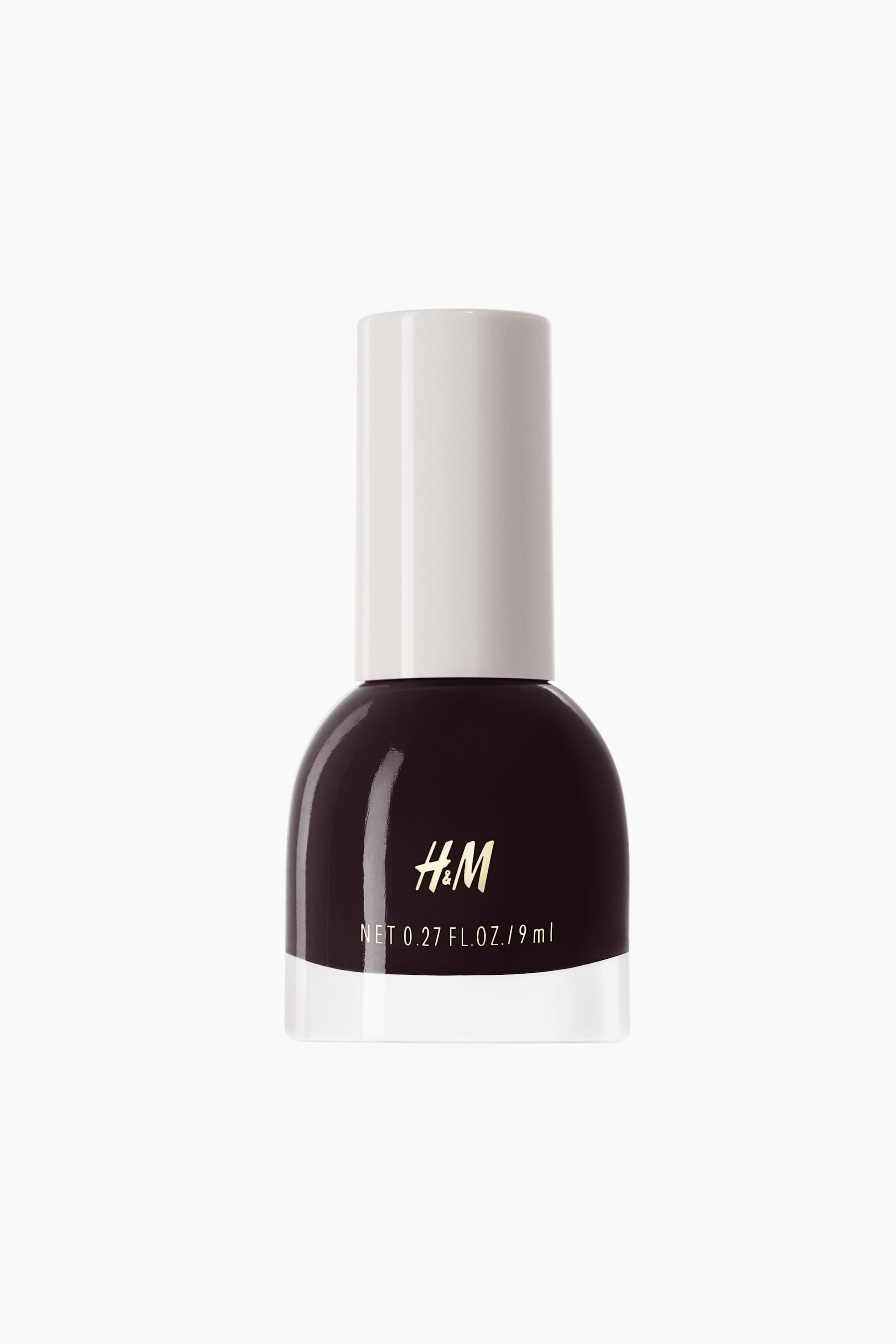 View larger image: A nail polish bottle is standing upright, showcasing a dark brown-burgundy polish, a clear glass base, and a white cap. The bottle's front is displaying the gold "H&M" logo and white text reading "NET 0.27 FL. OZ. / 9 ml".