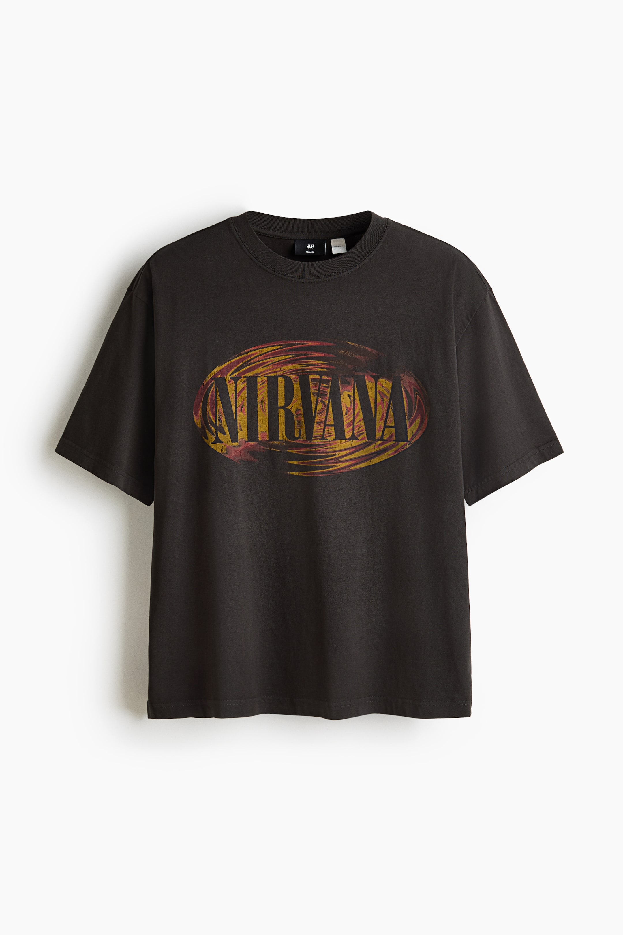 Agrandir l'image: Un t-shirt noir délavé à manches courtes présente un col rond et un grand motif ovale sur l’avant. Le motif affiche le mot « NIRVANA » en lettres sombres, sur un fond tourbillonnant de jaune, d’orange et de rouge.