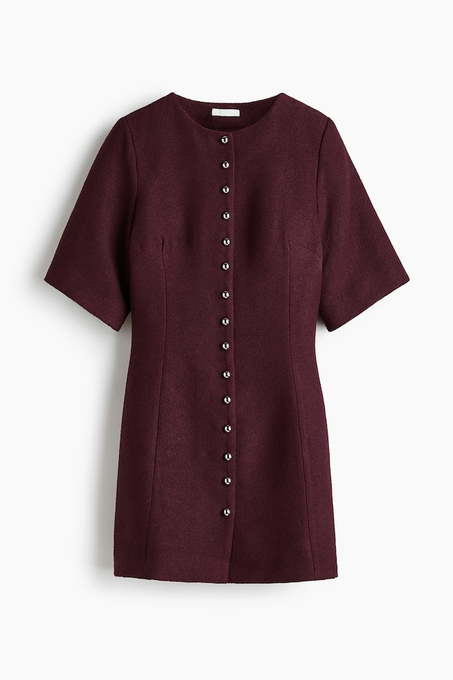 Une mini-robe bordeaux foncé est suspendue, avec un col rond et des manches courtes et larges. Une patte de boutonnage pleine longueur avec de nombreux boutons argentés descend le long du devant, et des coutures verticales façonnent sa silhouette ajustée. - 1