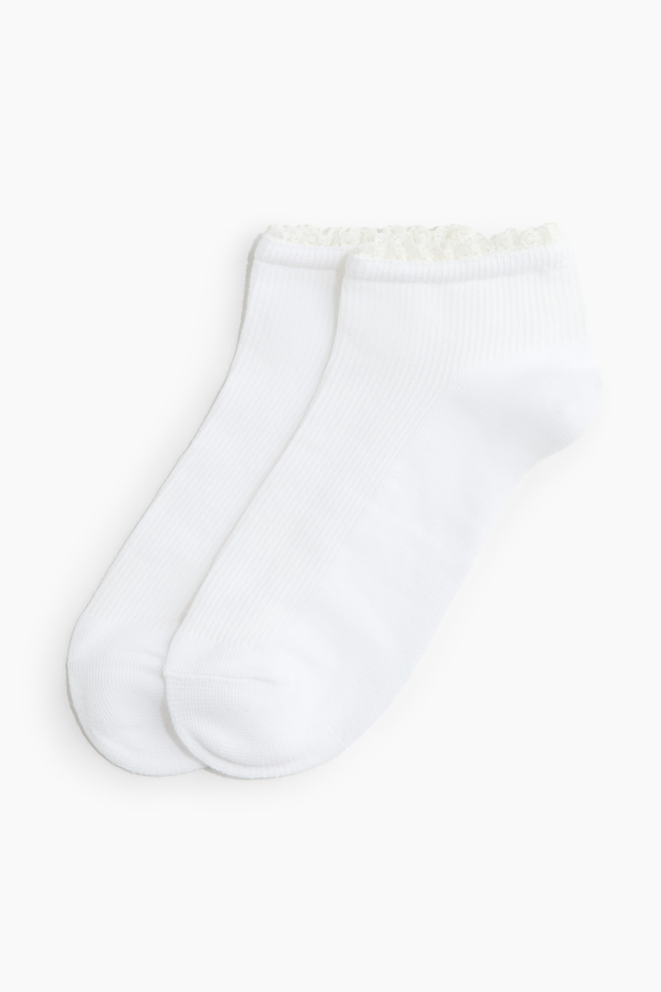 View larger image: A pair of white ribbed ankle socks is lying side by side. Each sock features a delicate, cream-colored ruffled trim along its top cuff.