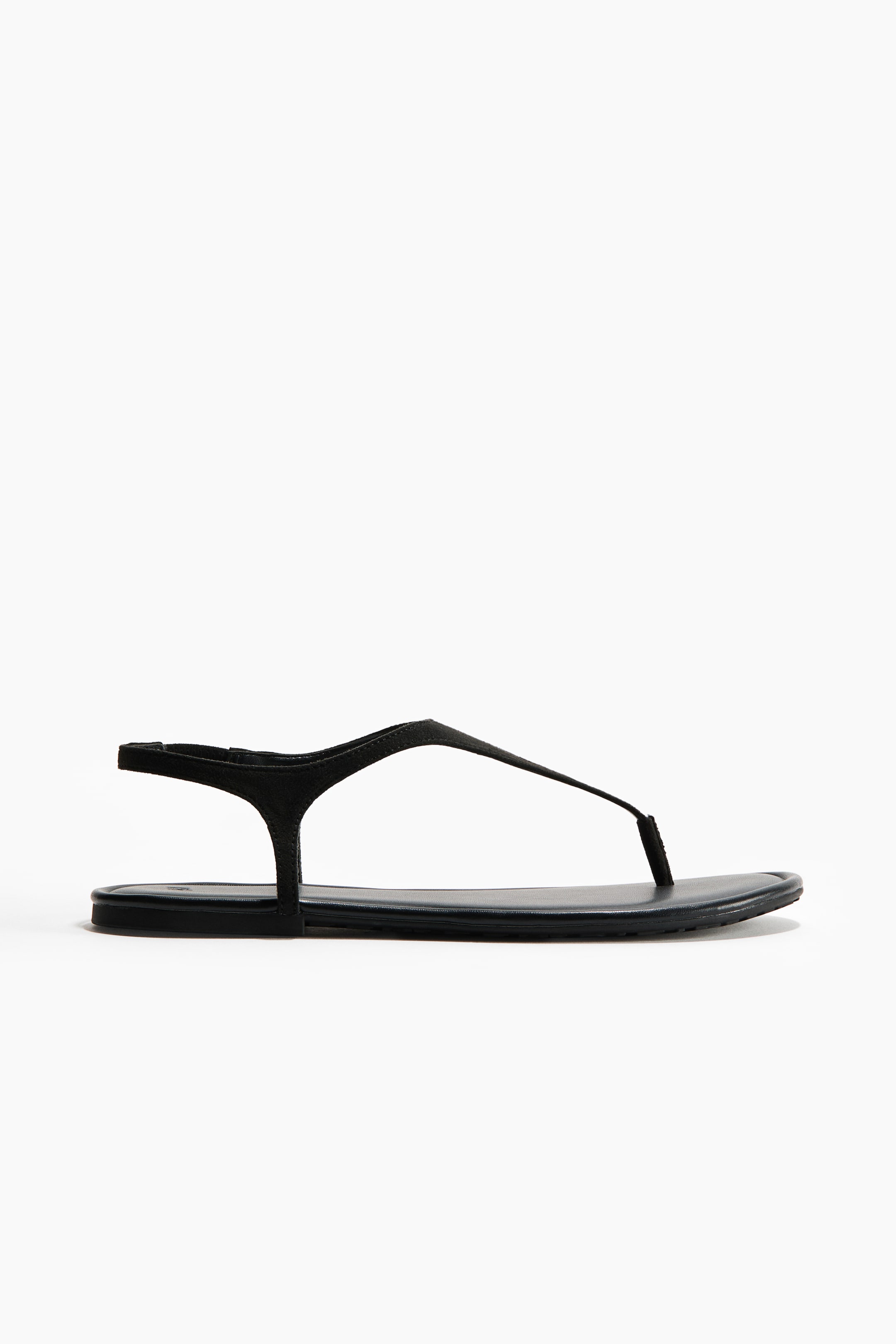 View larger image: A black thong sandal is presented in side profile. It features a thin toe-post strap that extends to connect with side straps, which then form a delicate ankle strap. The sandal is designed with a flat sole.