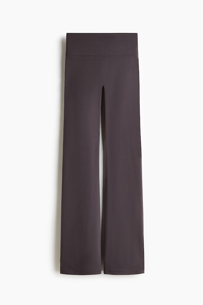 Flared Yoga leggings with SoftMove™ are showcased from the front in a dark grey colour, featuring a wide waistband. A prominent vertical slit extends down the front centre, and the legs flare towards the hem. - 1