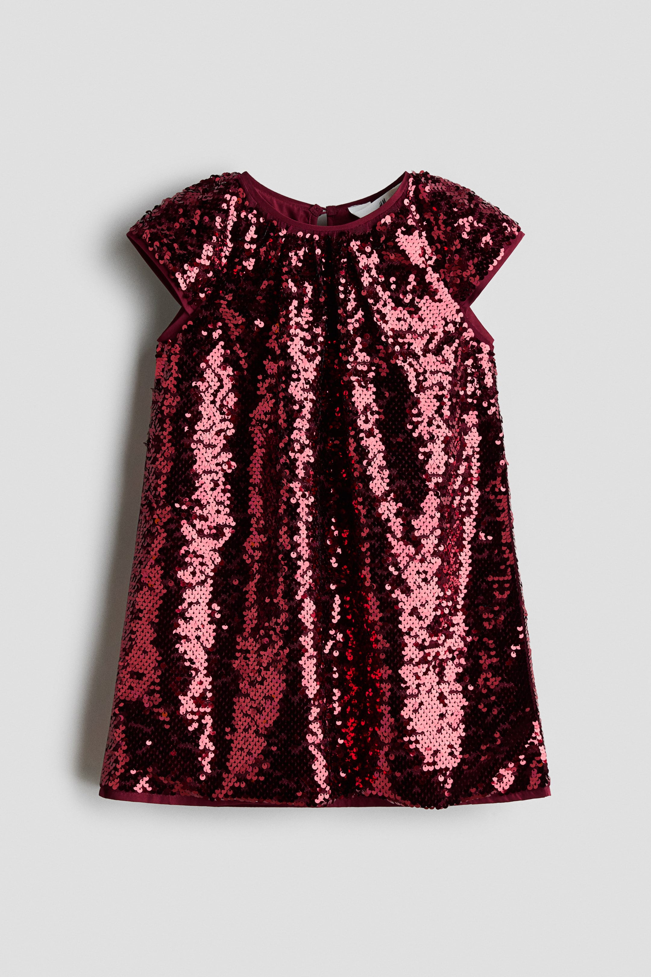 View larger image: A burgundy sequinned mesh dress is shown from the front, featuring a round neckline with subtle pleating and short cap sleeves. The A-line dress is covered in shimmering sequins and finished with solid fabric binding along the neckline, cuffs, and hem.