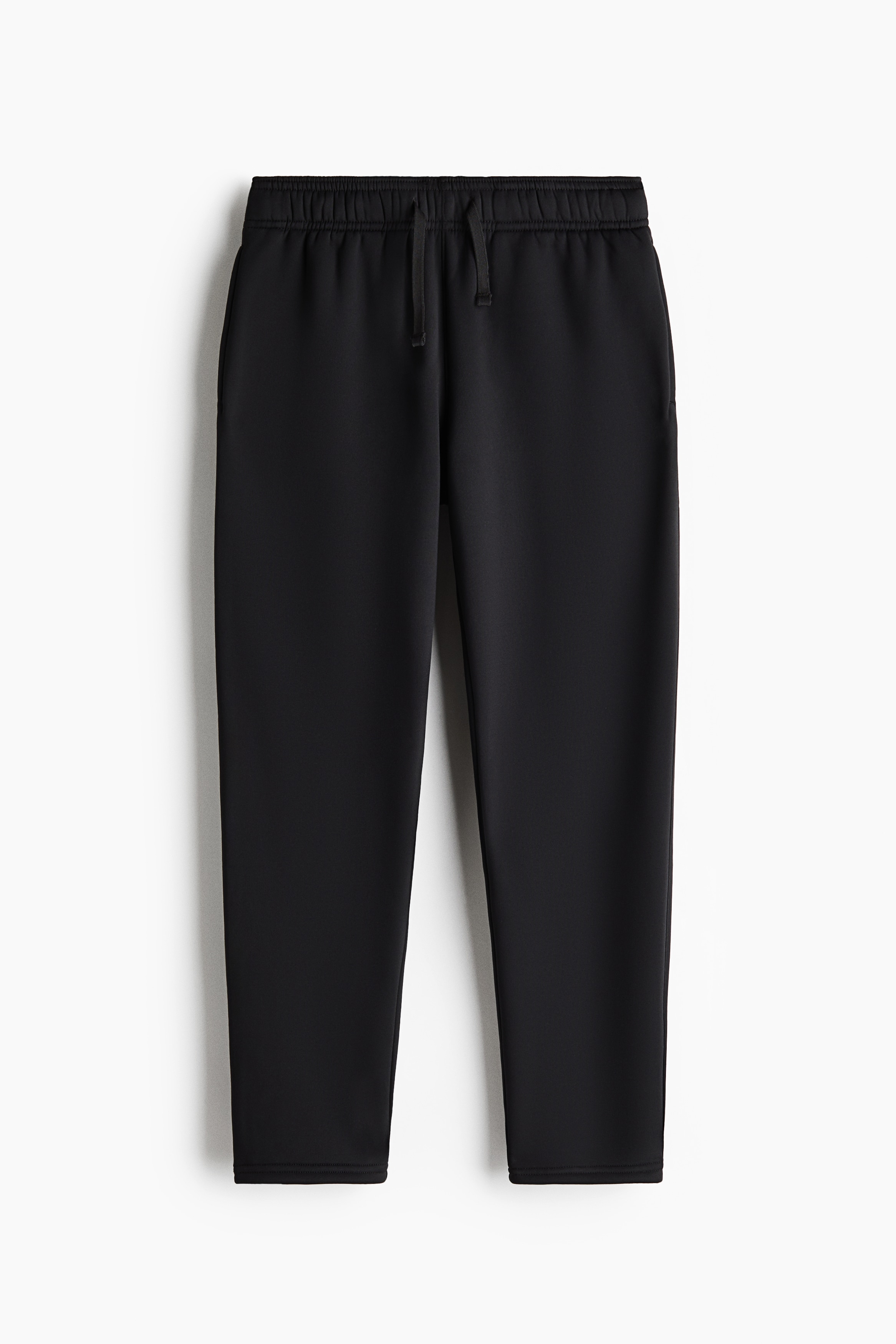 A dark grey fleece jacket featuring a high stand-up collar and a full-length zip is shown in side profile. The jacket is paired with matching black jogger trousers featuring elasticated cuffs that sit above black lace-up boots.