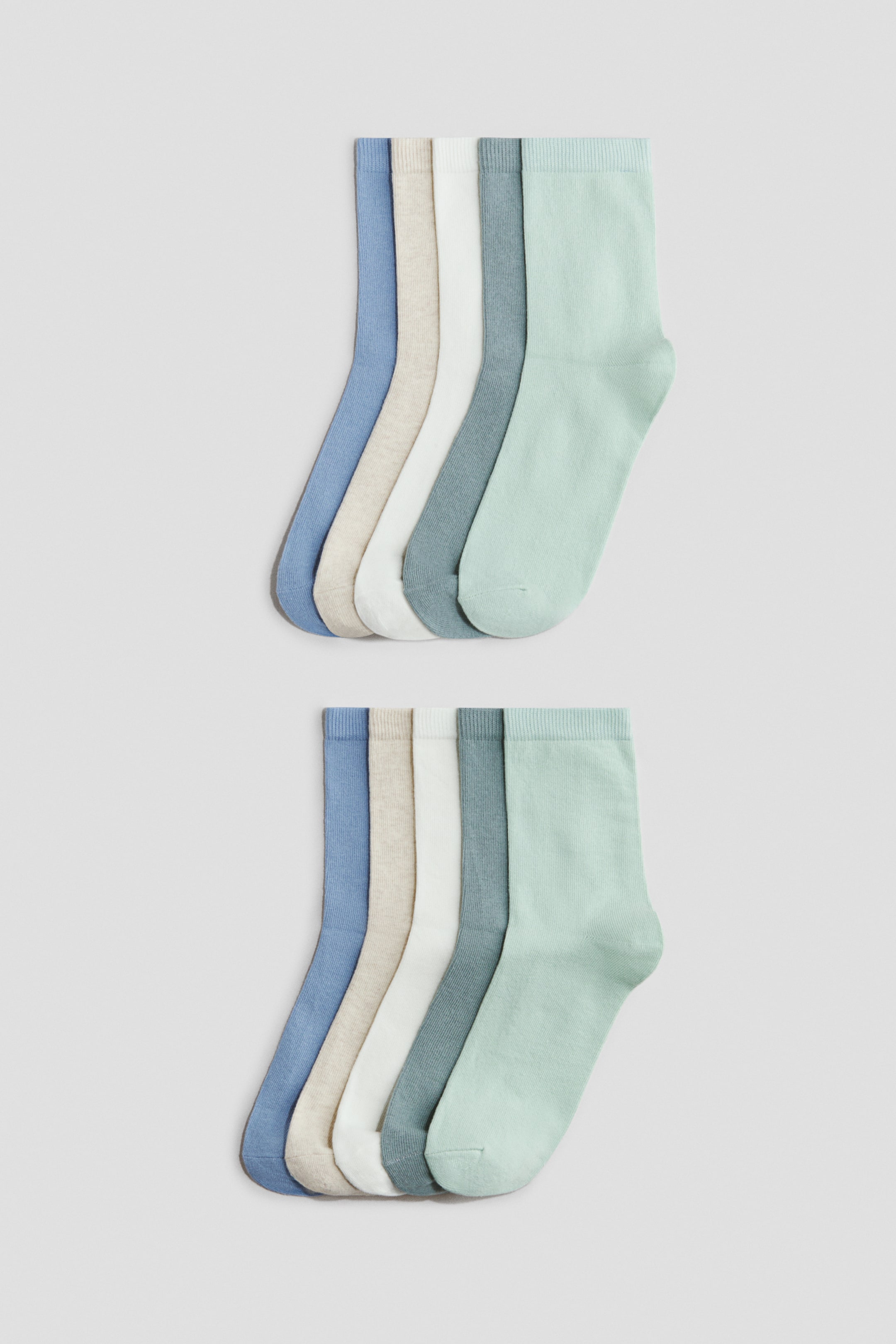 Größeres Bild ansehen: Weiche, fein gestrickte Socken liegen flach in zwei Reihen, wobei jede Reihe fünf Socken in Hellblau, Beige, Weiß, Graublau und Hellgrün zeigt und mit elastischen, gerippten Bündchen am oberen Ende versehen ist.
