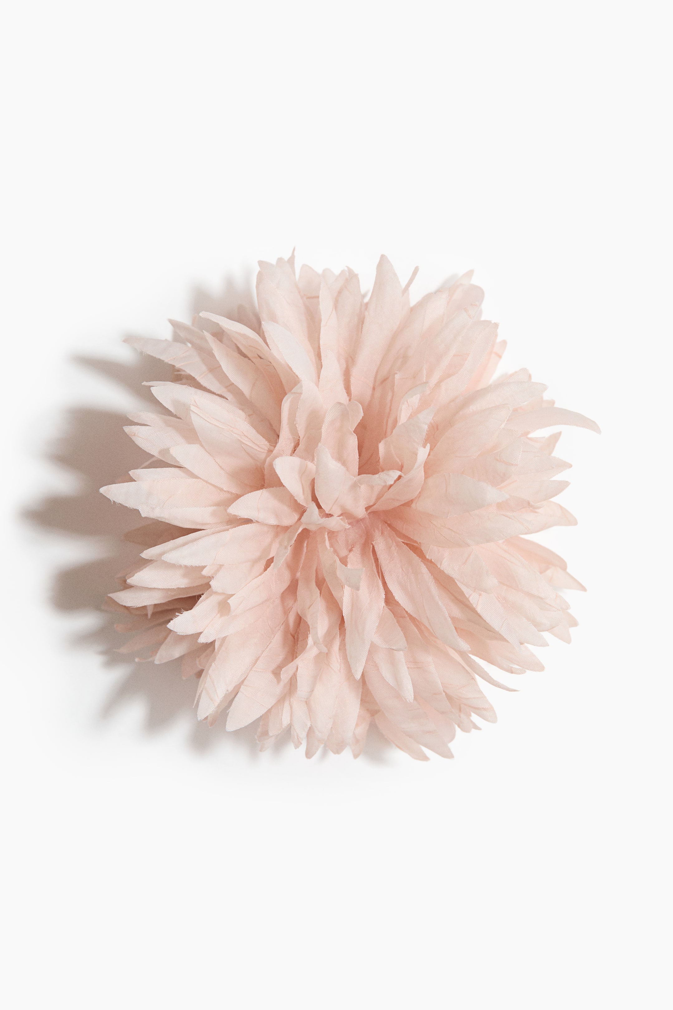 Visa större bild: En rosafärgad tygblomma visar upp sina många lager av skira tygblad. Dessa delikata blad bildar en fyllig, rundad blomma med en mjuk, voluminös textur.