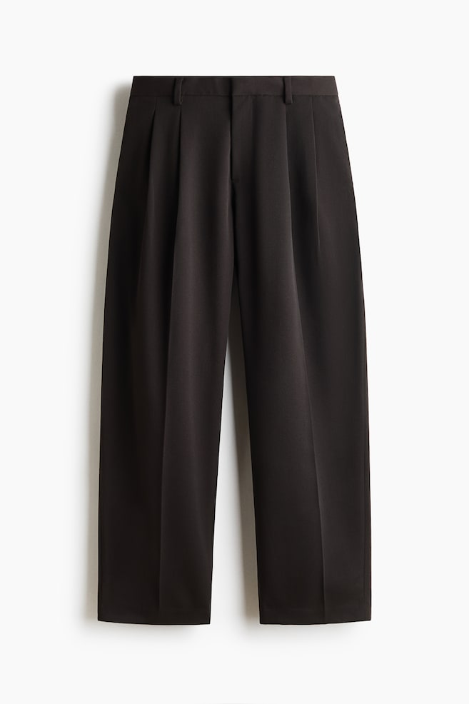 Eine dunkelbraune Hose ist von vorne zu sehen und verfÃ¼gt Ã¼ber einen Bund mit GÃ¼rtelschlaufen sowie doppelte Bundfalten auf der Vorderseite. Die Hose hÃ¤ngt in einer weiten, geraden Passform und zeigt scharfe BÃ¼gelfalten, die mittig Ã¼ber jedes Hosenbein verlaufen. - 1