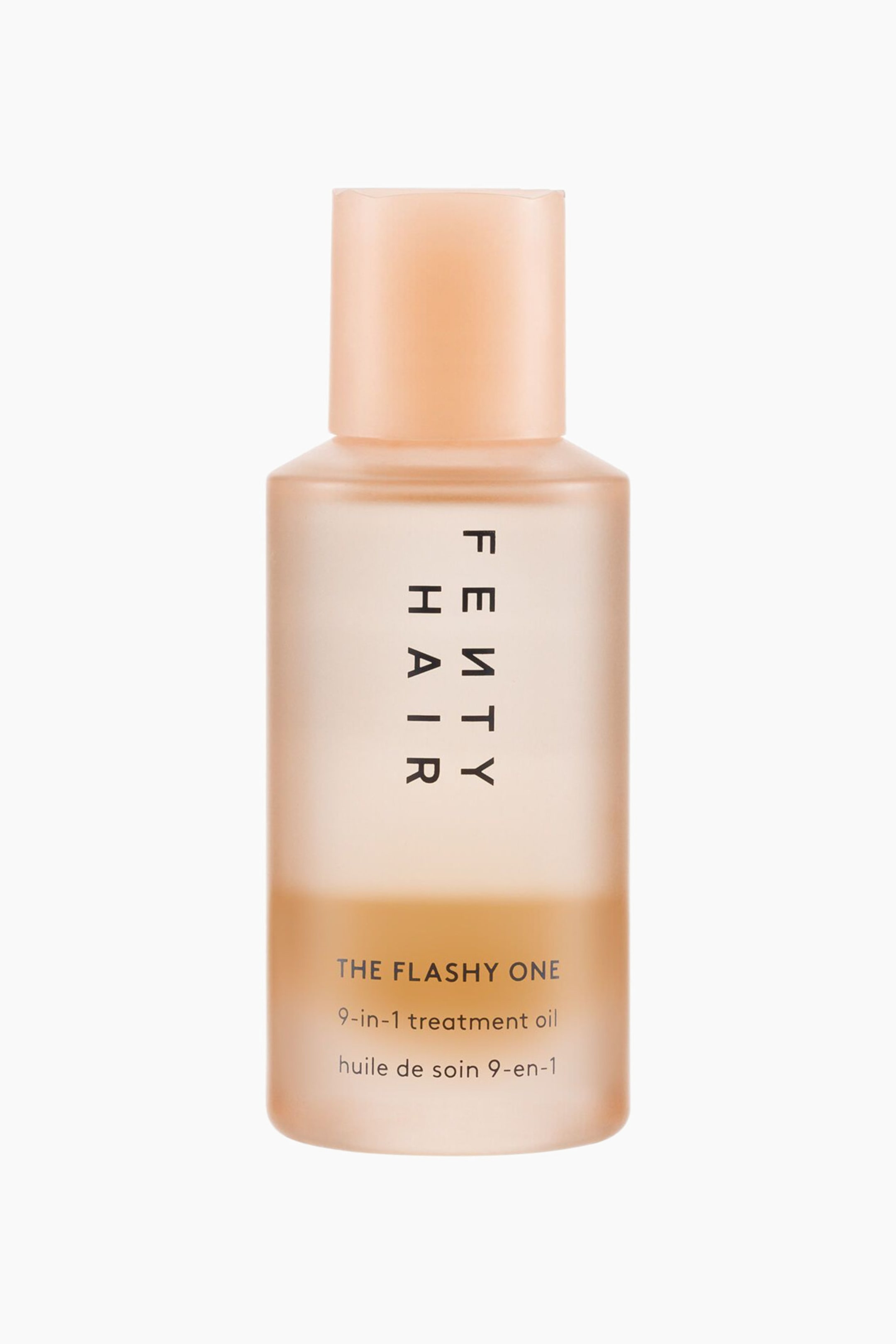 Visa större bild: The Flashy One 9-in-1 Treatment Oil står upprätt i en framifrån-vy och visar en frostad, halvgenomskinlig persikofärgad flaska med matchande ogenomskinligt cylindriskt lock. Flaskan har vertikala svarta bokstäver med "FENTY HAIR" längs mitten och horisontell produkttext nära basen, vilket avslöjar en gyllene bärnstensfärgad vätska inuti.