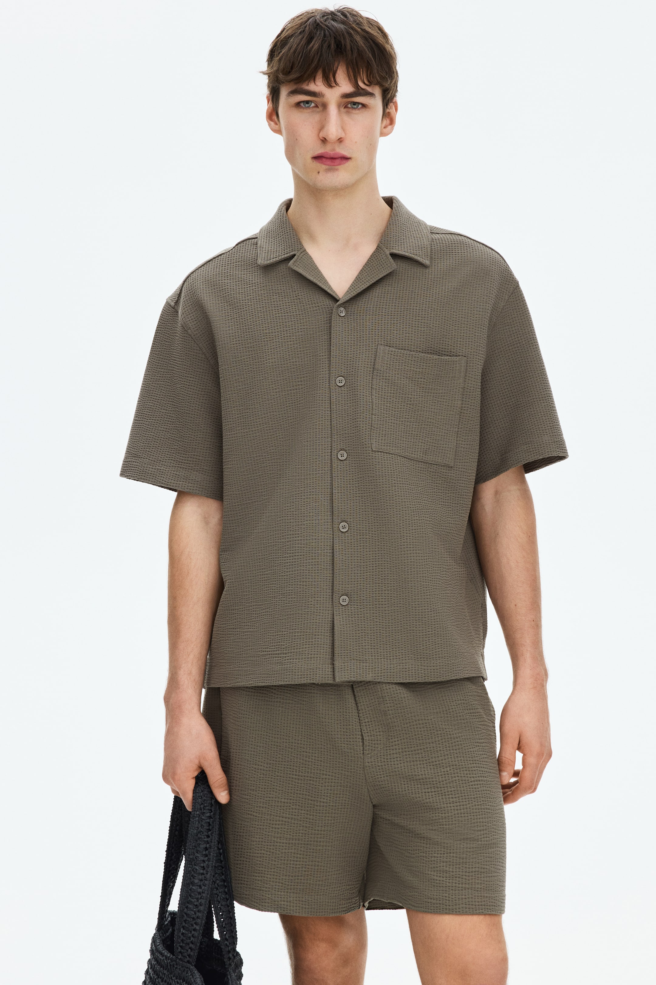 View larger image: A khaki green waffle-textured short-sleeve shirt and matching shorts set is showcased. The shirt features a camp collar, a full button-front closure, and a chest patch pocket, while the shorts offer a relaxed fit with a flat front waistband.