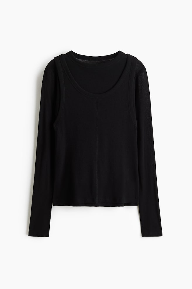 A black layered top is facing front, showcasing a long-sleeve crew-neck underlayer worn beneath a ribbed tank-top overlay that features a deep scoop neckline and a vertical seam running down the center. - 1