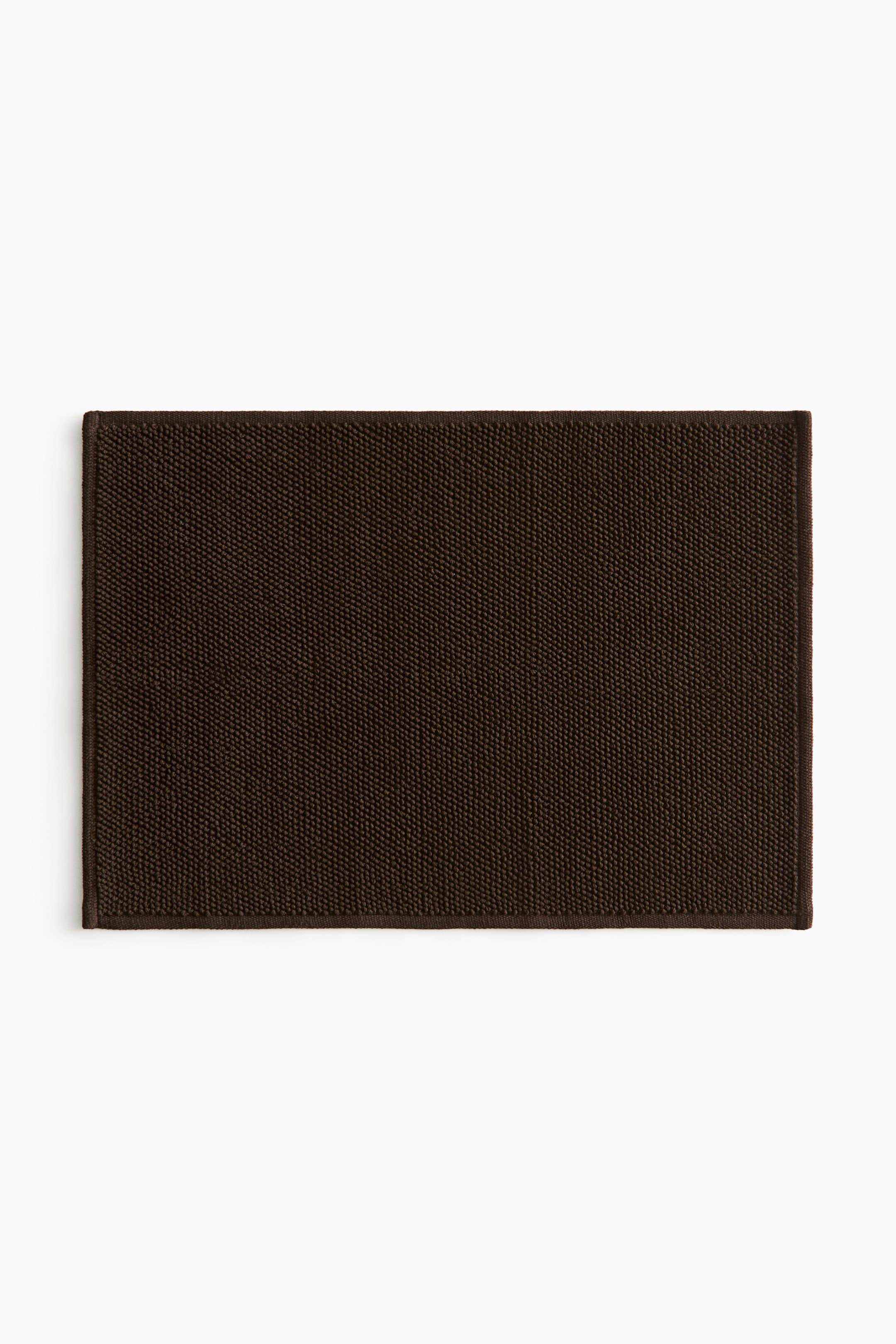 View larger image: Presenting a dark brown rectangular bath mat with a finely woven, textured surface. The edges are neatly finished.