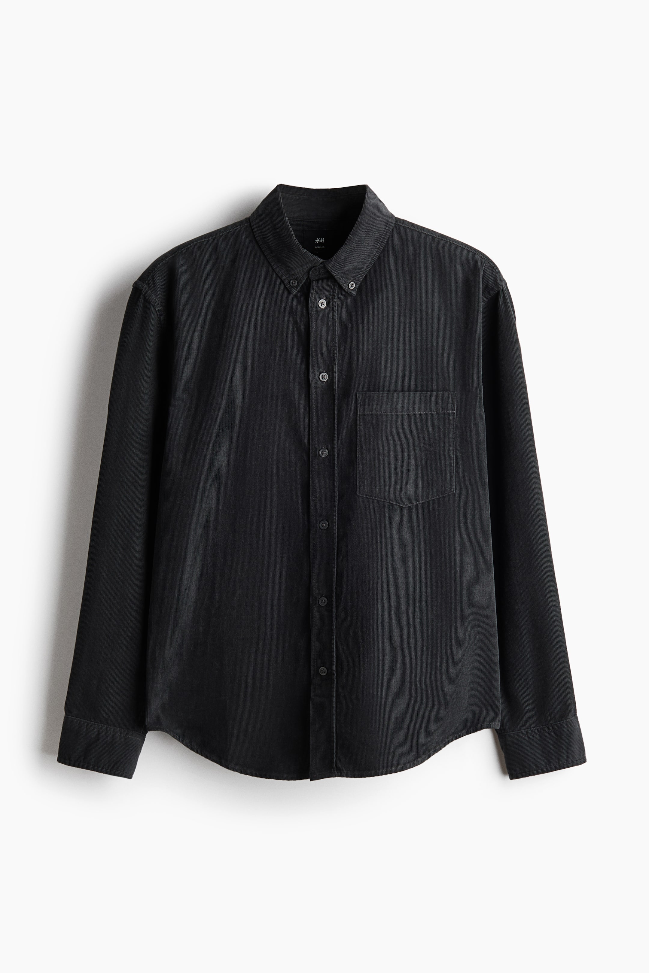 Se større billede: En vasket sort denimskjorte vises forfra. Den har en button-down-krave, en gennemgående knaplukning med synlige knapper og en enkelt påsyet brystlomme på venstre side. Lange ærmer med knappede manchetter og en buet kant er også synlige.