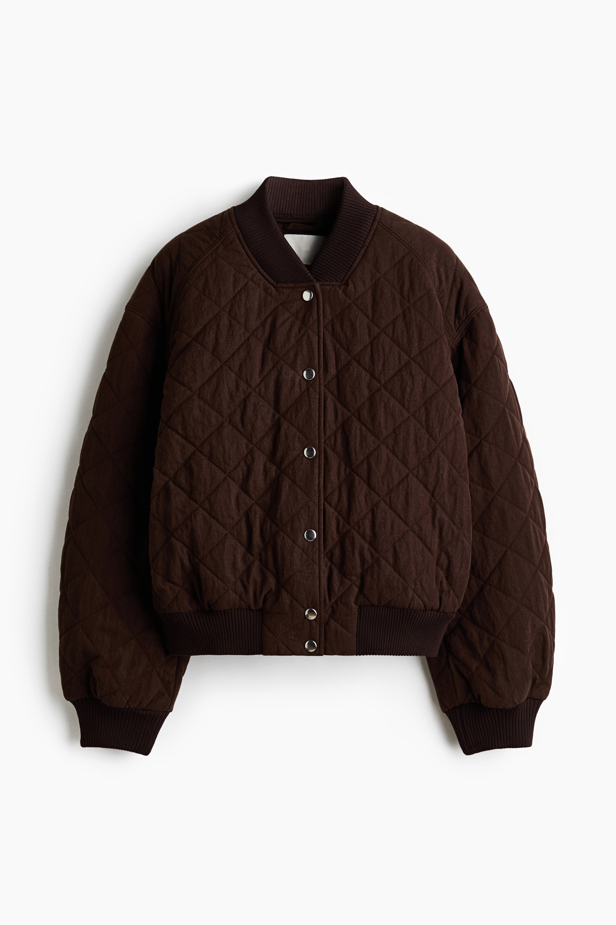 View larger image: A brown quilted bomber jacket is shown facing forwards, featuring a ribbed collar, ribbed cuffs and a ribbed hem. It displays a diamond quilted pattern throughout and silver snap buttons down the centre front.