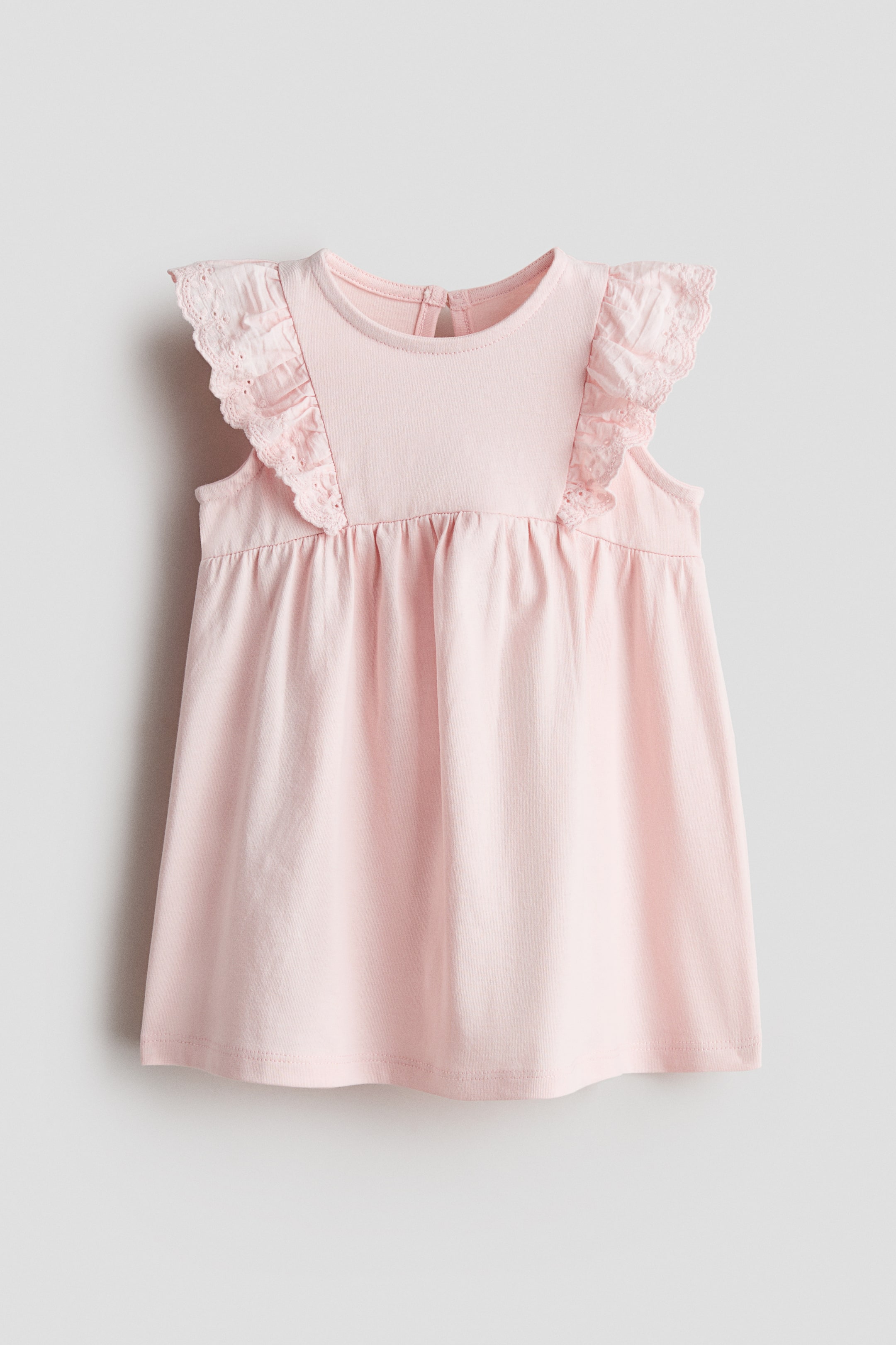 Agrandir l'image: Robe rose sans manches en jersey de coton, ornée de volants en tissu tissé avec des détails en broderie anglaise aux épaules. Elle est conçue avec un col rond, une ouverture en goutte d'eau à l'arrière, des fronces à la taille, et une jupe évasée.