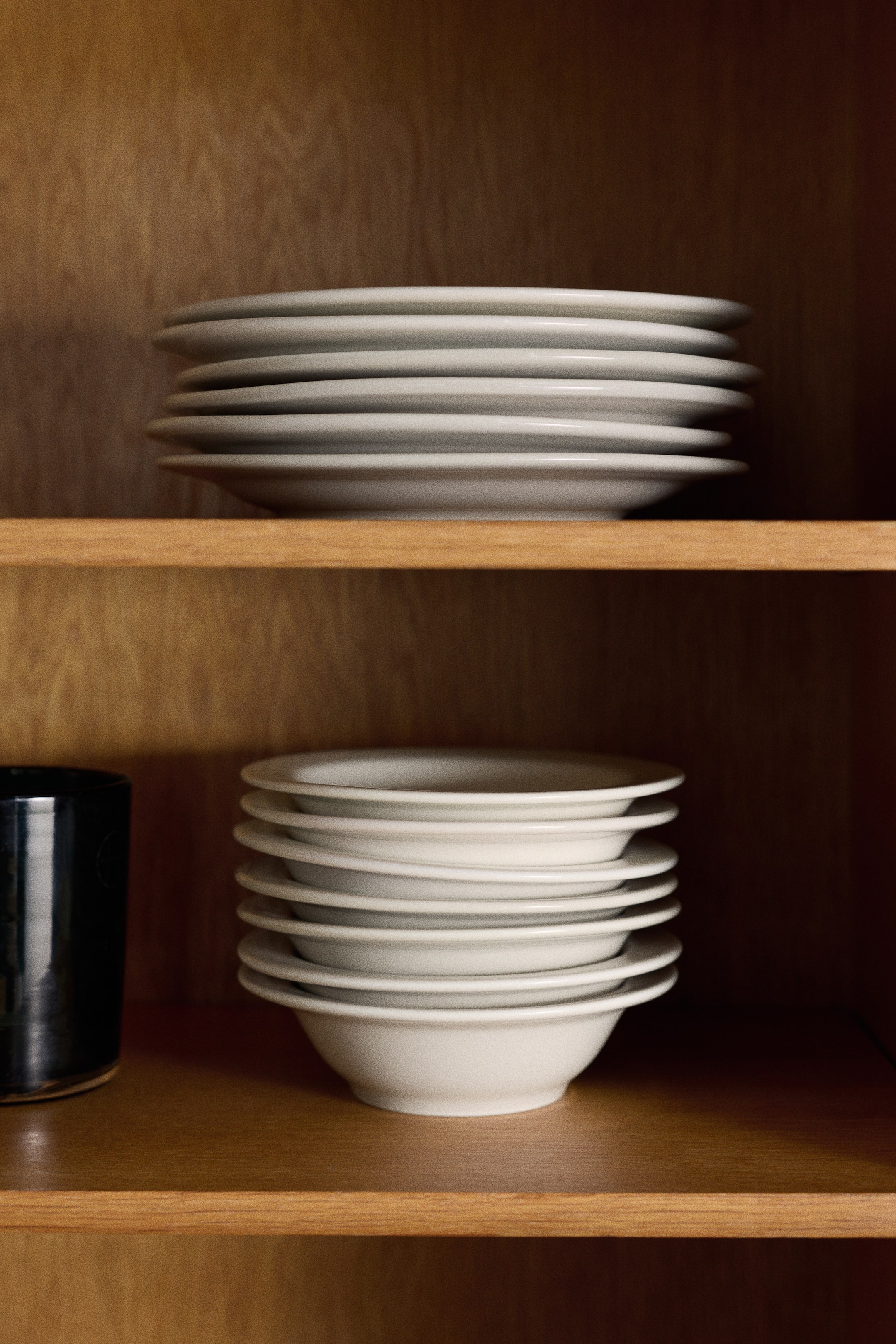View larger image: Small porcelain bowls featuring a minimalist design with a classic rim are stacked vertically in a front-facing view, showcasing their shallow profile and smooth, off-white glaze.