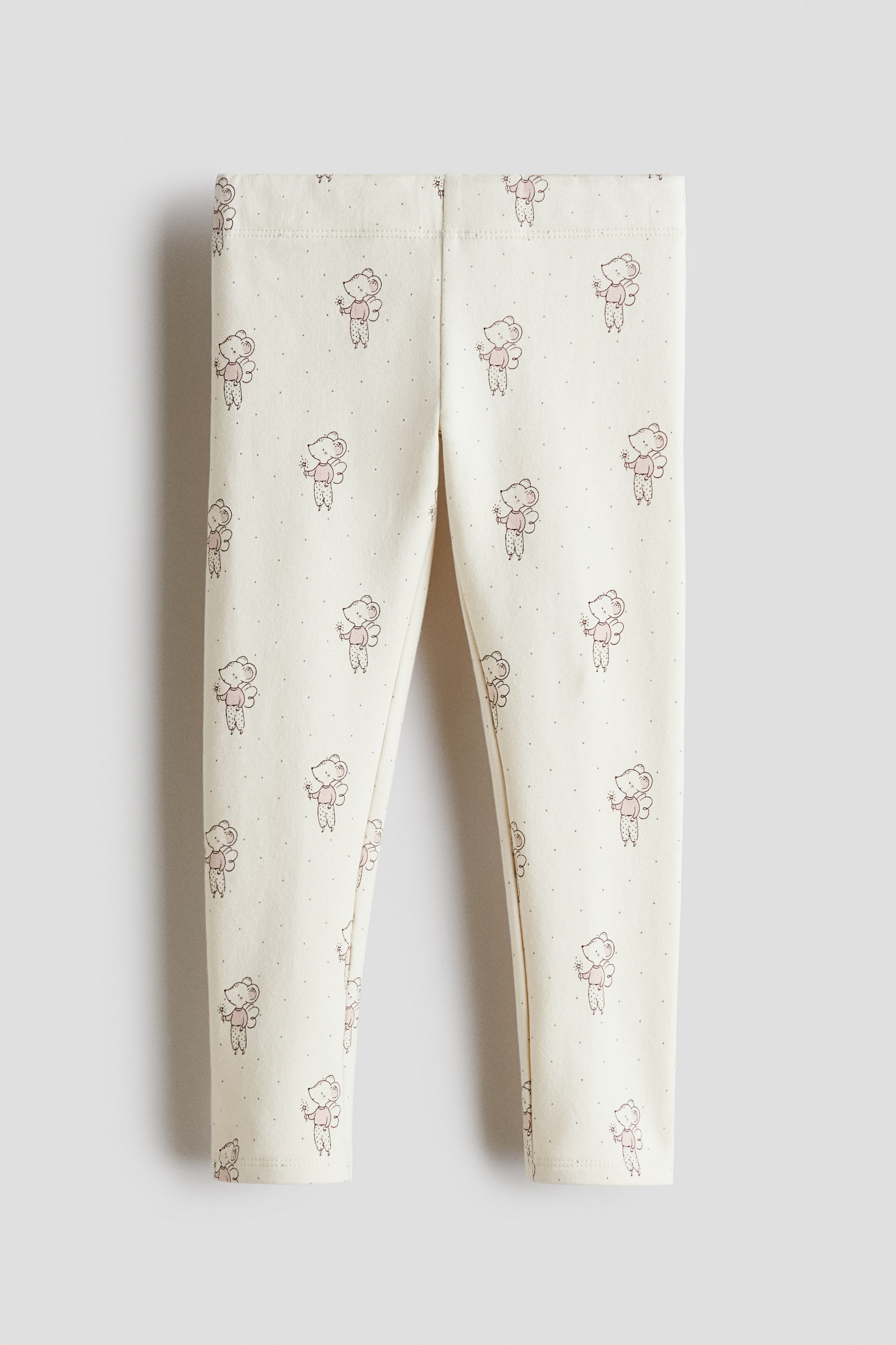 Größeres Bild anzeigen: Cremefarbene Leggings liegen flach ausgebreitet in einer Vorderansicht und zeigen ein Allover-Muster aus kleinen Comic-Mäusen mit Flügeln, die Zauberstäbe halten und mit rosa Oberteilen sowie gepunkteten Unterteilen bekleidet sind, durchsetzt mit kleinen Punkten. Ein elastischer Bund ist oben sichtbar.