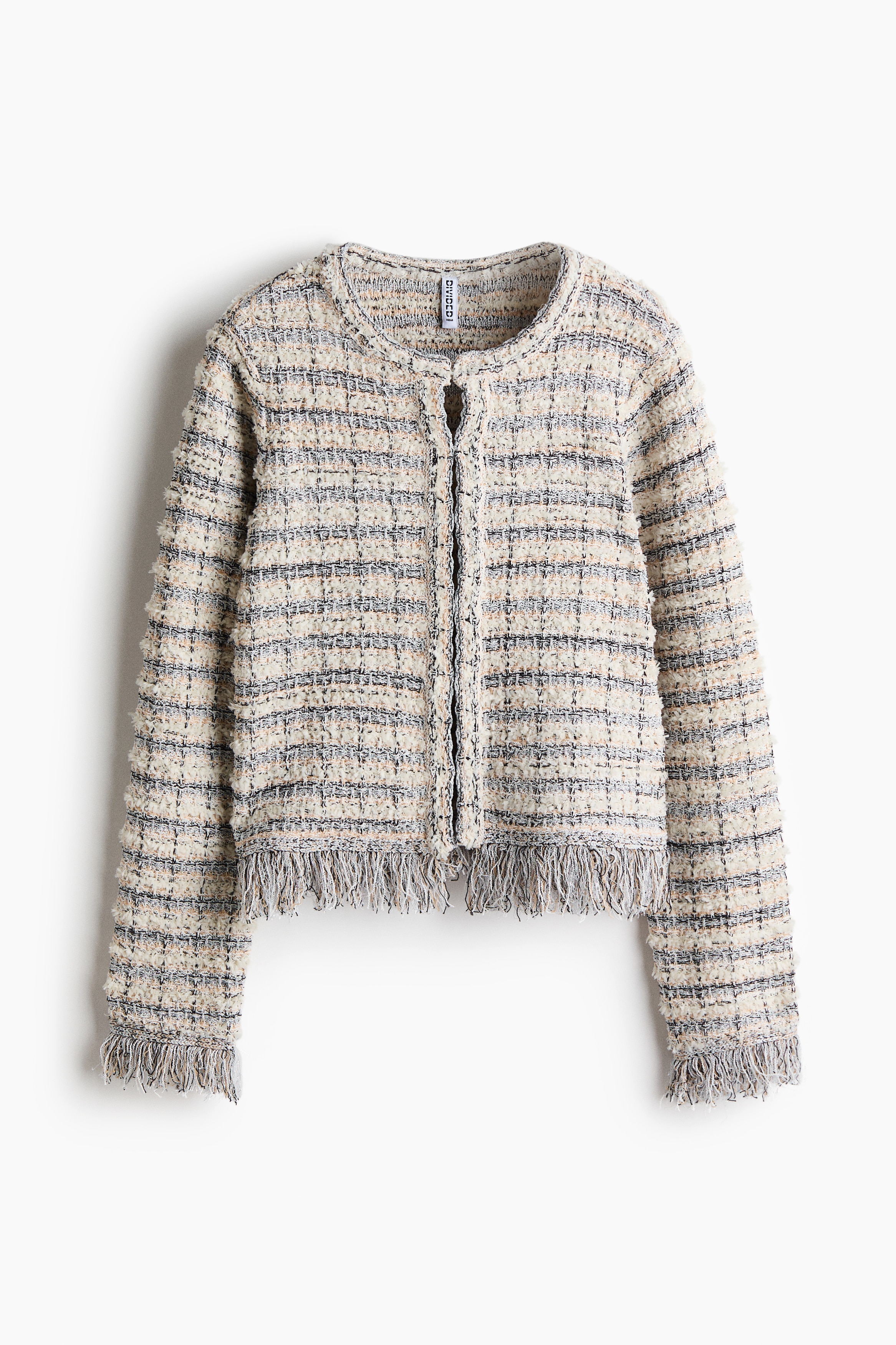 A cropped tweed jacket with horizontal blue and cream stripes and fringe trim at the hem and cuffs is being worn by the model. The jacket is paired with light-wash, wide-leg denim jeans.