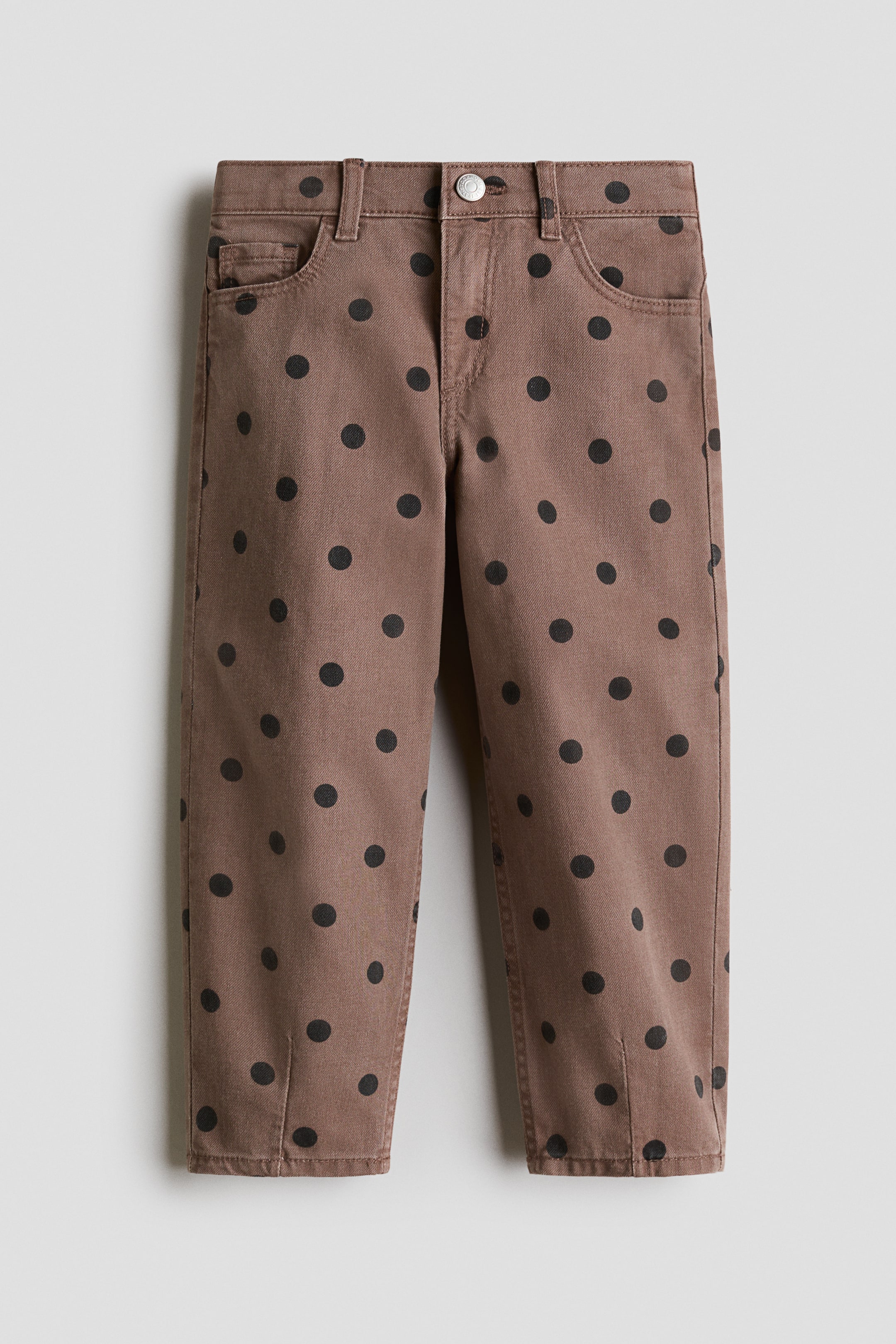 View larger image: The 5-pocket pants are shown from the front, crafted from brown cotton twill with a black polka dot design. They feature a zip fly with a button closure and barrel legs with darts at the hems.