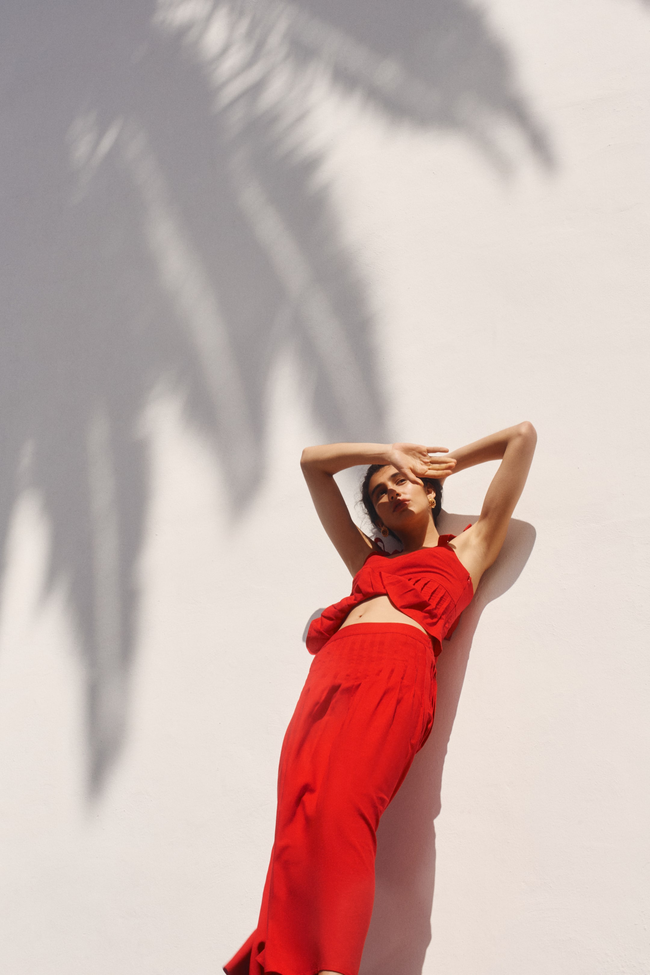 View larger image: Presenting a red calf-length skirt crafted in a blend of linen and viscose, showcasing its front and side. It features a high waist with pleats around the top, gracefully flaring out to the hem.