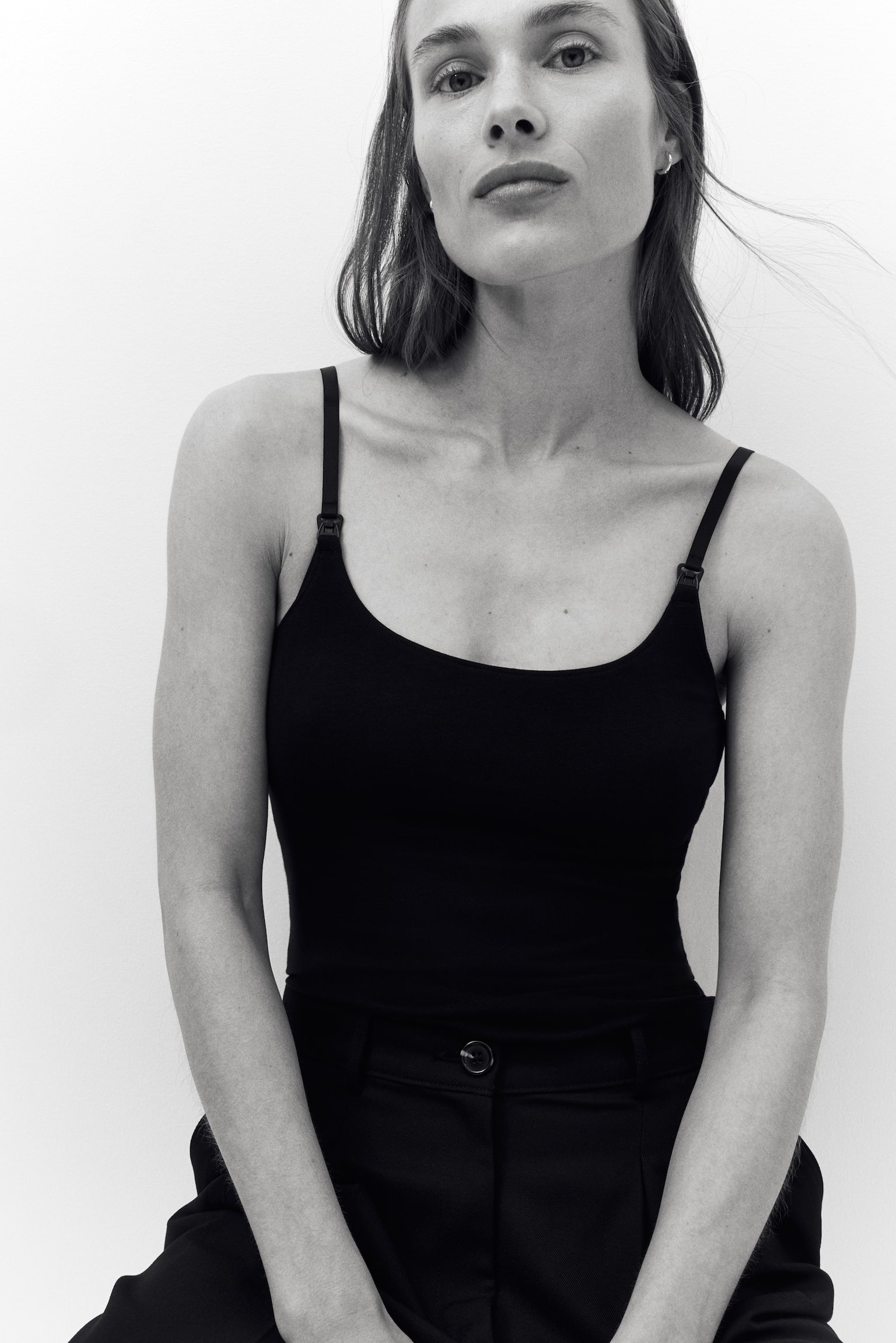 The model is wearing a black nursing top, which features slim, adjustable shoulder straps with practical fastenings for nursing access. - 1