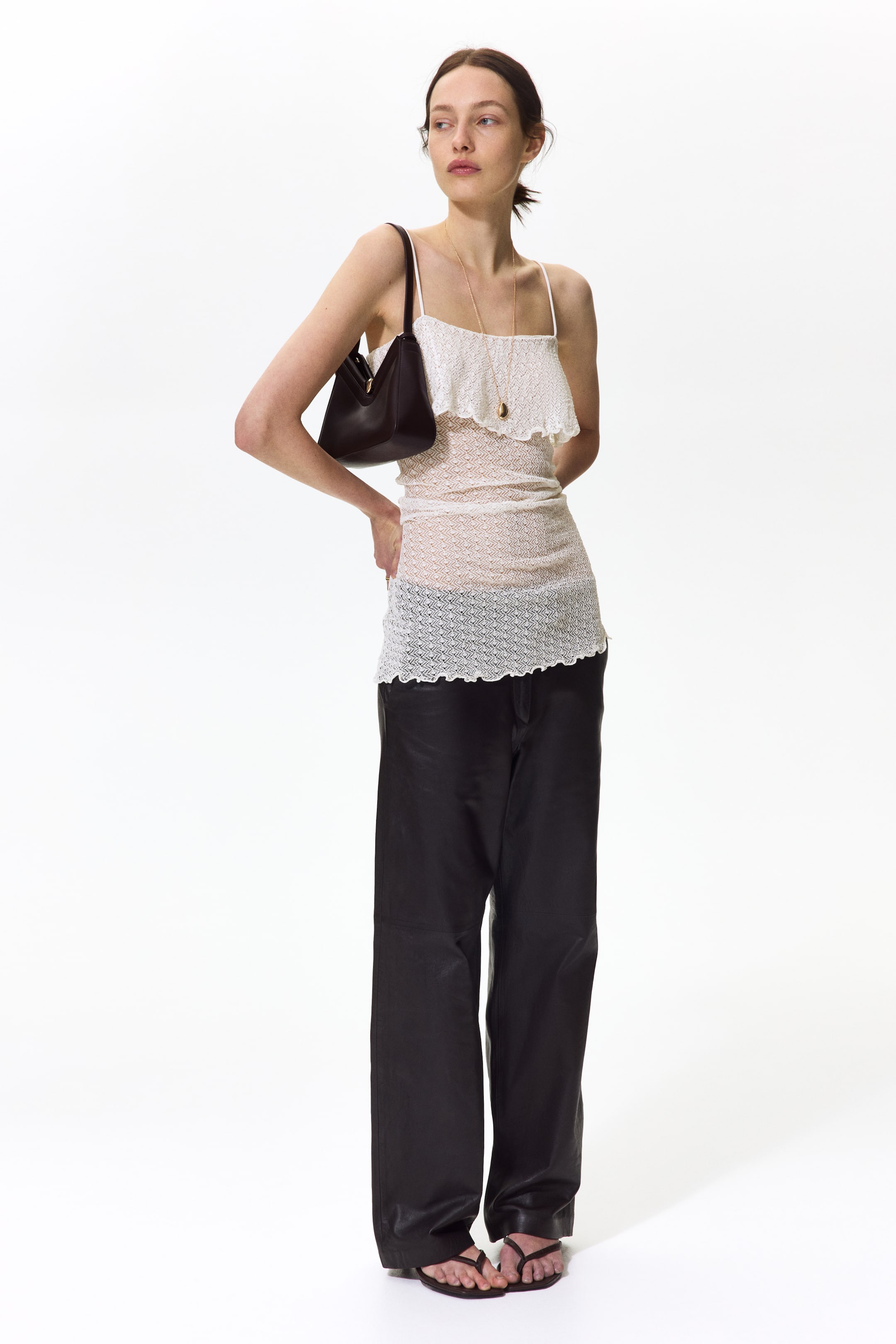 View larger image: Black wide-leg trousers showcase a relaxed, full-length silhouette with a slightly glossy finish, allowing the fabric to pool elegantly around the feet.