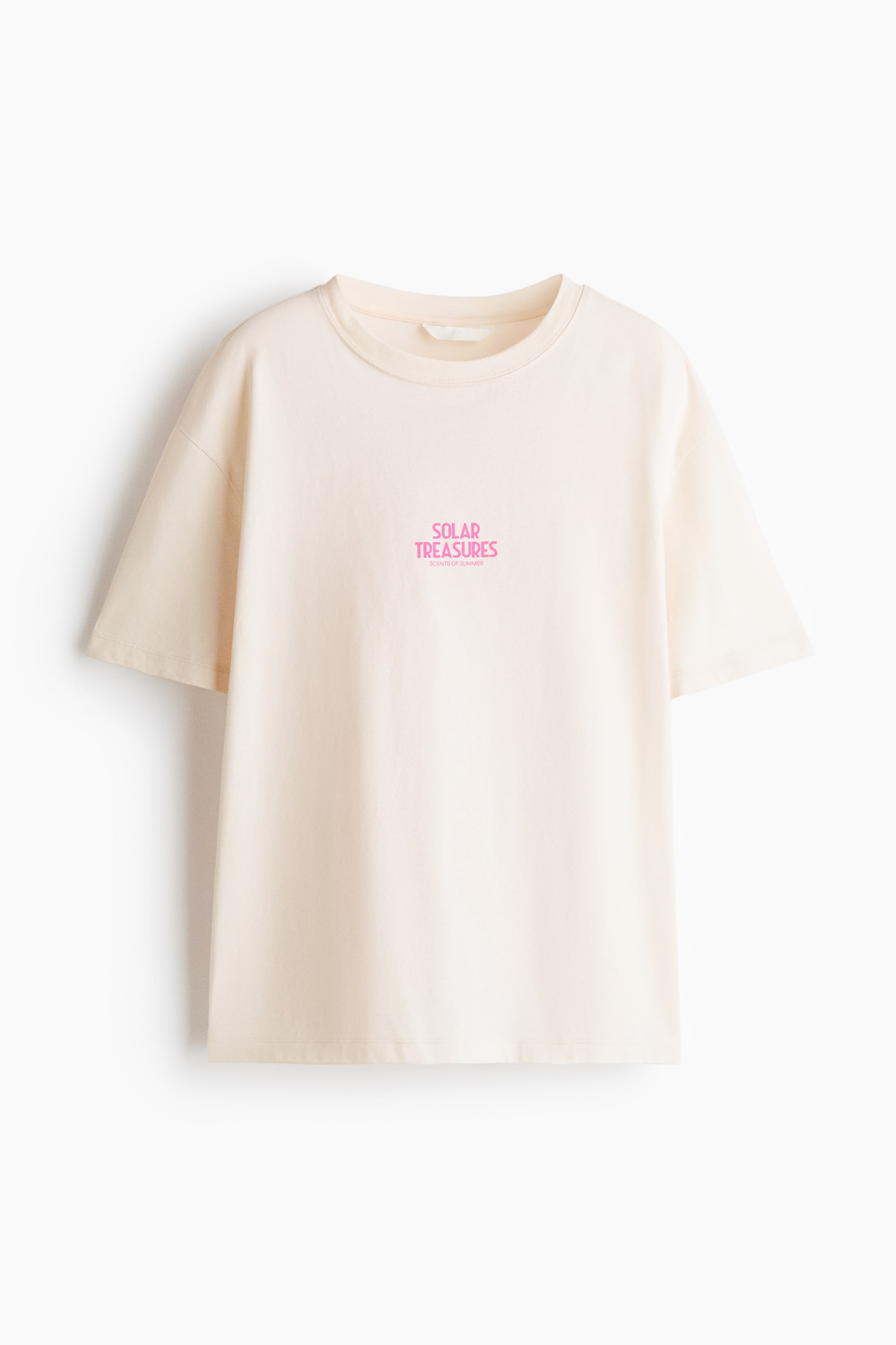 View larger image: An oversized cotton jersey t-shirt showcases a light cream shade, facing FRONT. It features a round neckline, subtly dropped shoulders, and a pink text graphic at the center front reading 'SOLAR TREASURES' with 'SCENTS OF SUMMER' below.