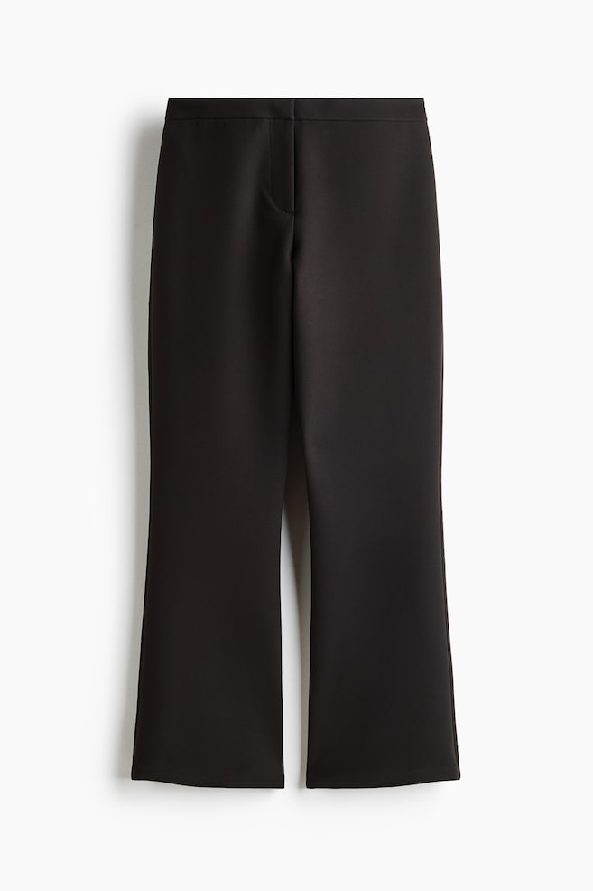 These black trousers are shown from the front, featuring a clean, flat waistband with a concealed front fastening and cropped legs that flare slightly towards the hem. - 1
