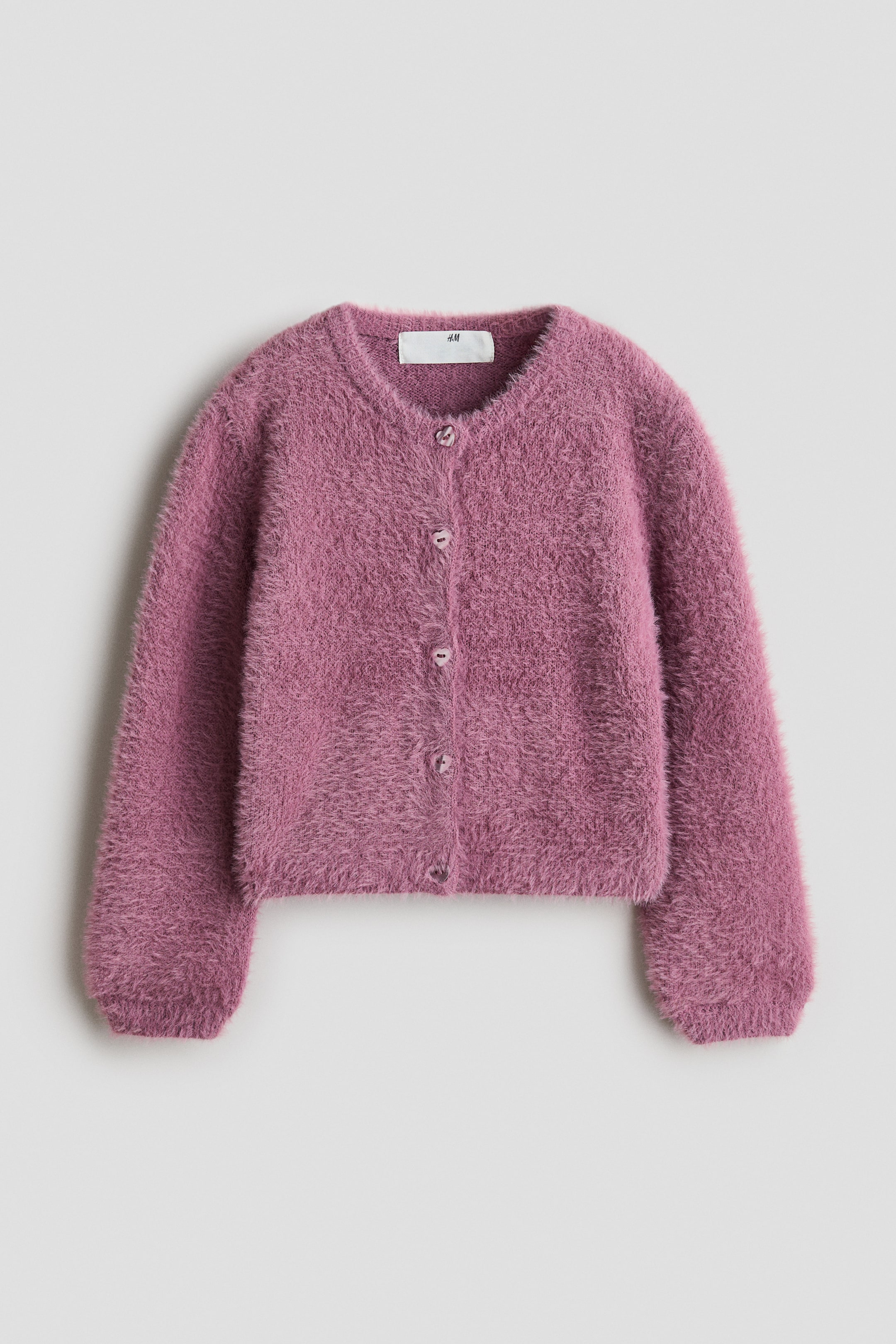 Vis større bilde: En rosa, fluffy strikket cardigan presenteres fra forsiden, med en rund, ribbekantet hals, hjerteformede knapper langs fronten, og lange ballongermer med ribbede mansjetter og en ribbet kant nederst.