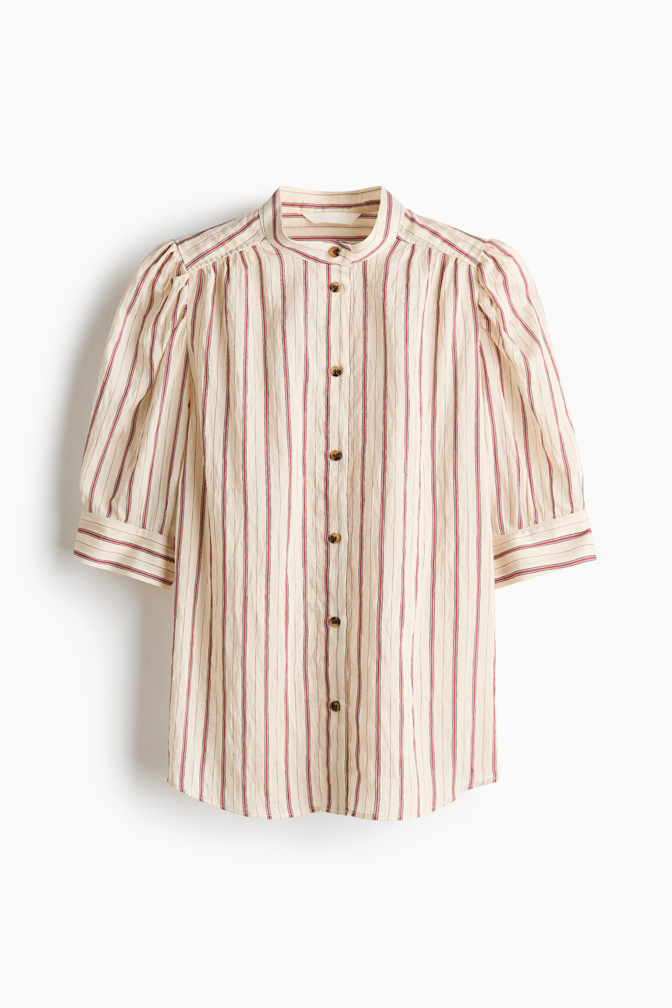 Ver imagen más grande: Una blusa beige de frente está adornada con rayas verticales rojas y finas rayas oscuras sobre una tela arrugada. Está diseñada con un cuello mao, mangas abullonadas de tres cuartos con puños simples y un cierre completo de botones en la parte delantera con pequeños botones marrones.