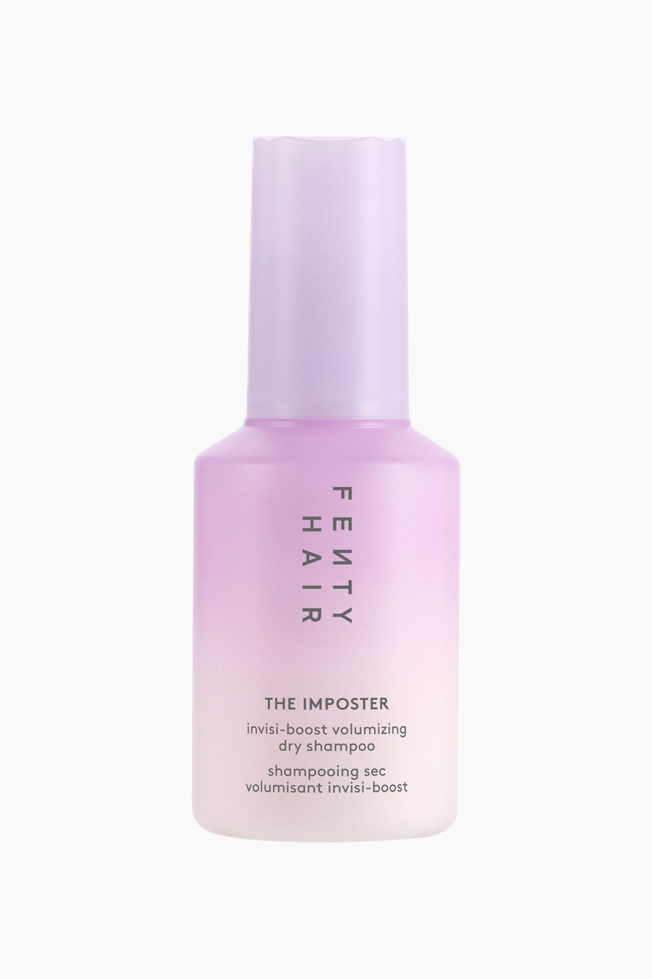 Visa större bild: The Imposter Volumizing Dry Shampoo Powder står upprätt i en frontvänd vy och har en cylindrisk flaska med en mjuk färgövergång från lavendelviolett upptill till blek rosa vid basen. Flaskan visar en hög, matchande ljuslila kork med vågformad övre kant och mörkgrå text tryckt på framsidan, inklusive den vertikala logotypen "FENTY HAIR" och produktbeskrivningar.