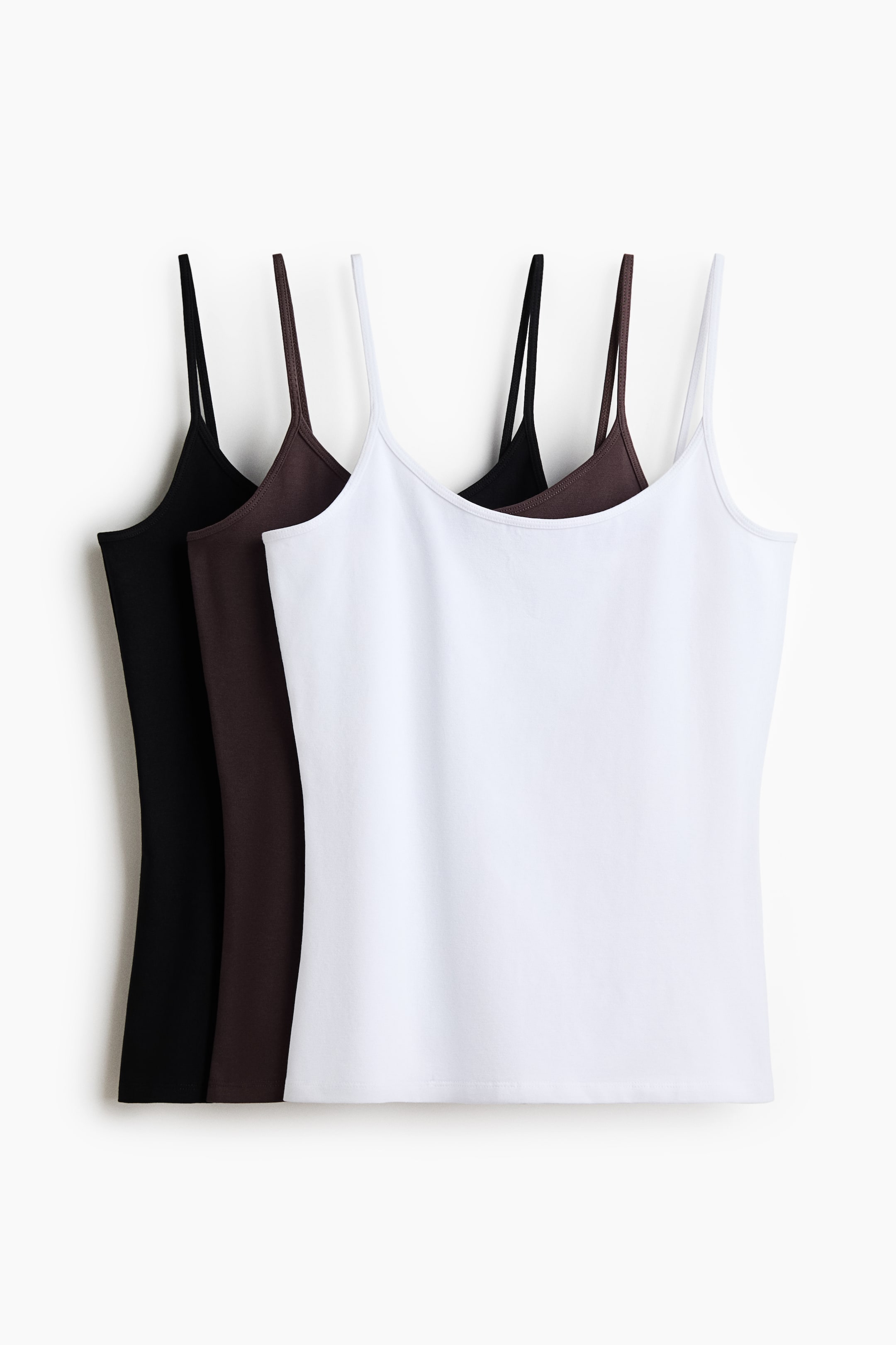 Ver imagen más grande: Tres tops ajustados en jersey de algodón con escote redondo y tirantes finos se presentan de frente. Están disponibles en blanco, marrón y negro.