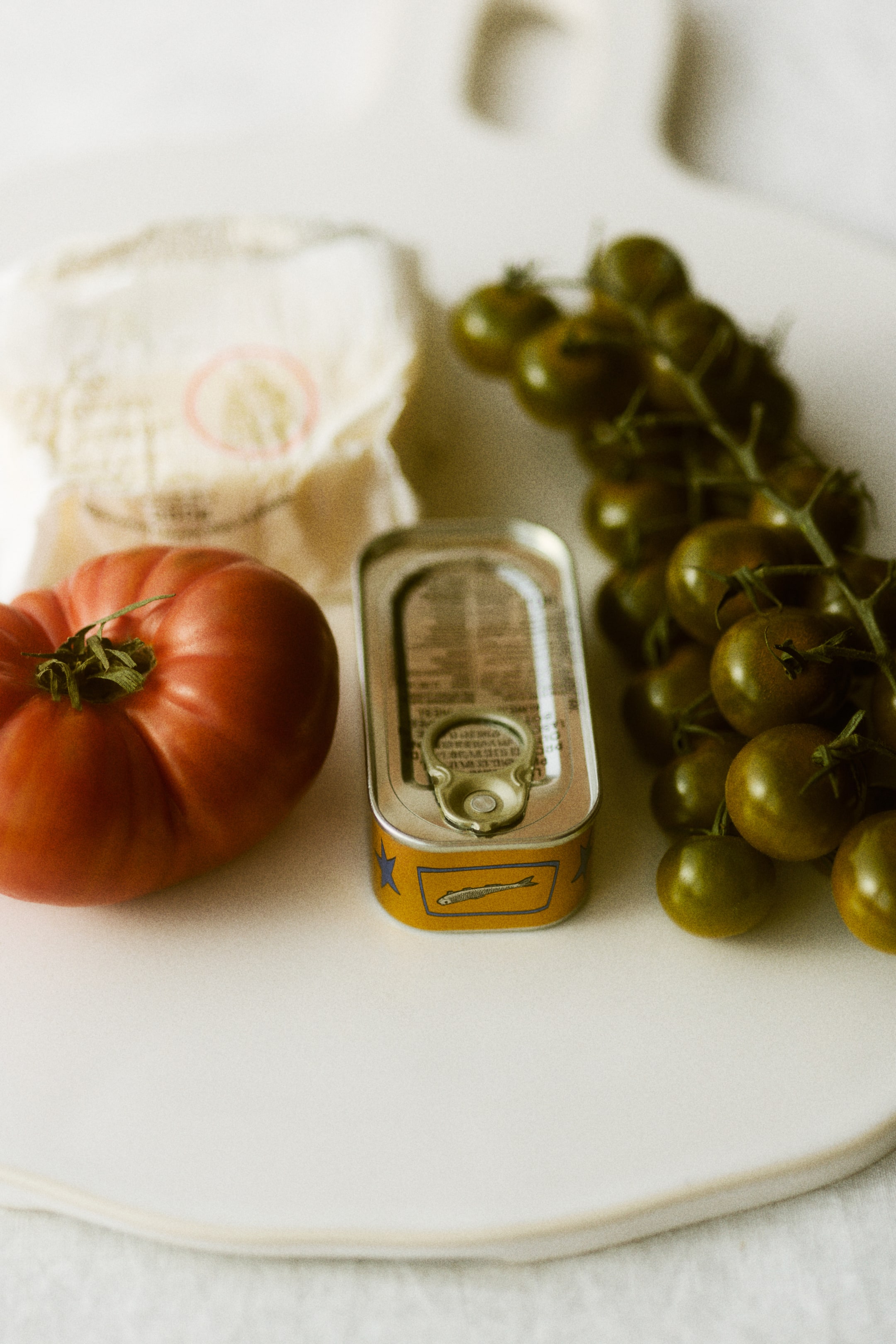 Nagyobb kép megtekintése: Egy szardíniás konzerv áll függőlegesen, sárga testtel, kék csillagokkal és egy kék téglalap alakú címkével, amelynek elején egy ezüst hal illusztráció látható. A tetején egy ezüst színű nyitófül mechanizmus található.