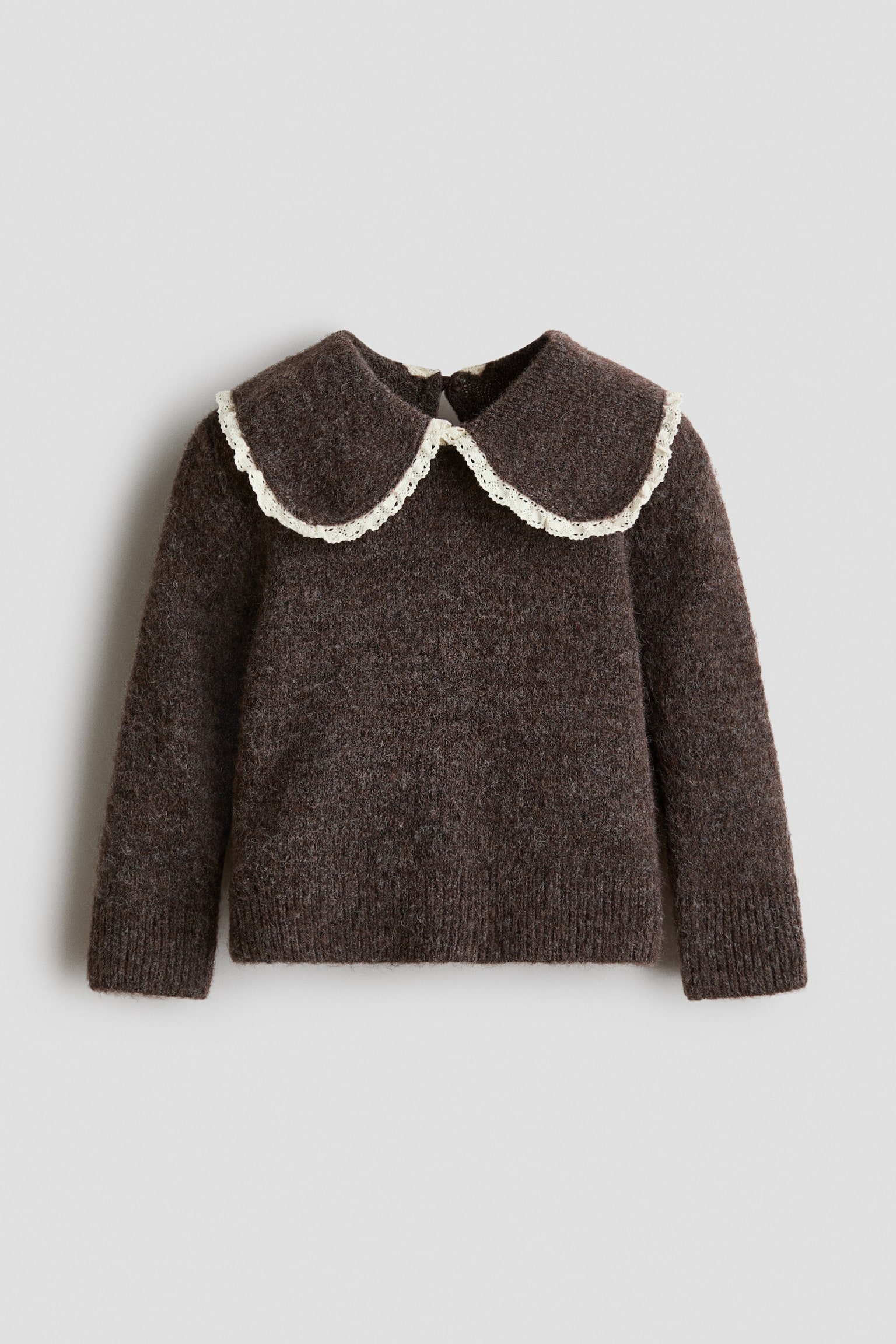 A dark brown sweater in a soft, brushed knit is shown from the front, featuring an oversized collar trimmed with delicate off-white lace. The sweater showcases a round neckline with a subtle keyhole opening at the back, long sleeves with wide ribbed cuffs, and a matching ribbed hem.