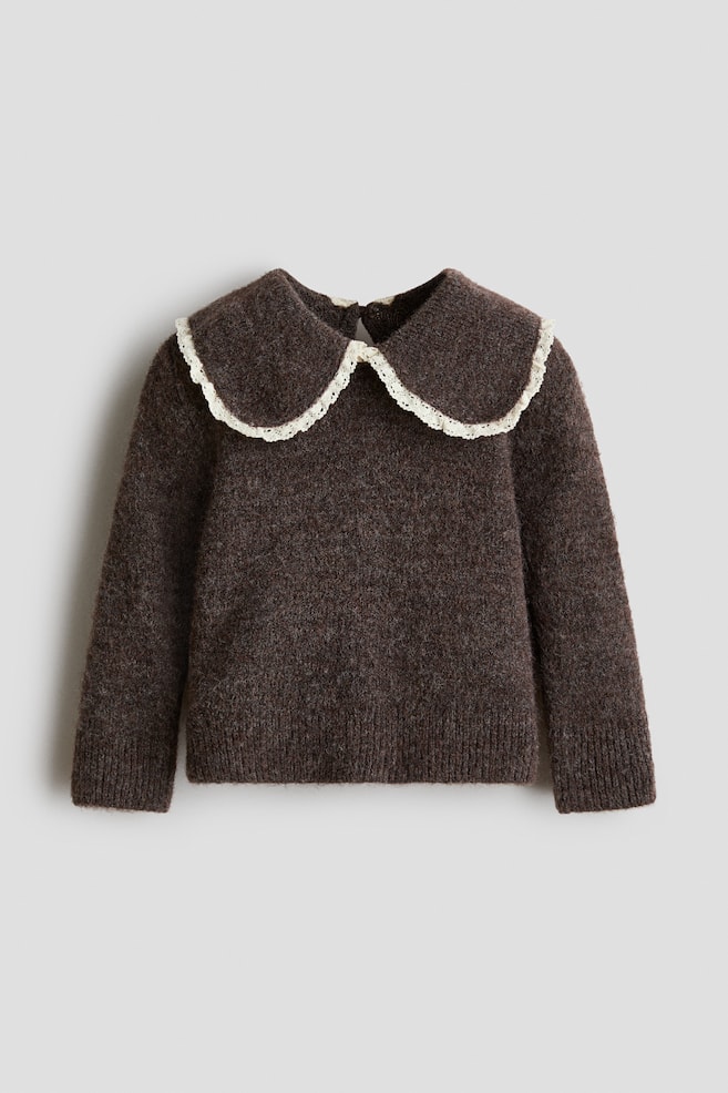 A dark brown jumper in a soft, brushed knit is shown from the front, featuring an oversized collar trimmed with delicate off-white lace. The jumper showcases a round neckline with a subtle keyhole opening at the back, long sleeves with wide ribbed cuffs, and a matching ribbed hem. - 1