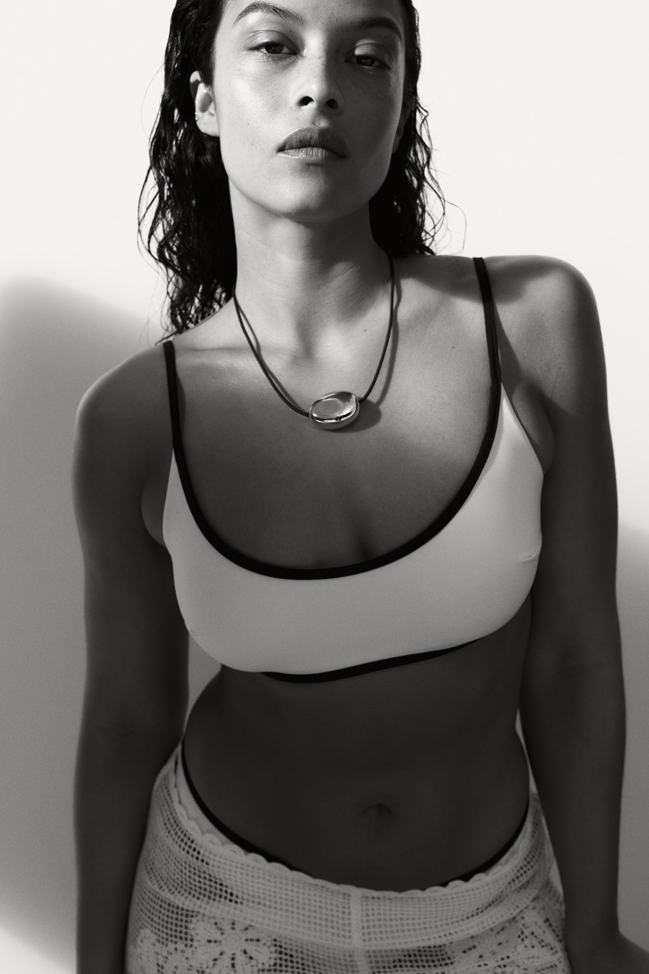 Преглед на по-голямо изображение: Оригинален текст: "Колие с тъмно въже и голямо, неправилно оформено, полирано сребристо оцветено висулка, която лежи на гърдите на носещия, обърната напред и отразяваща светлината от гладката си, изпъкнала повърхност."